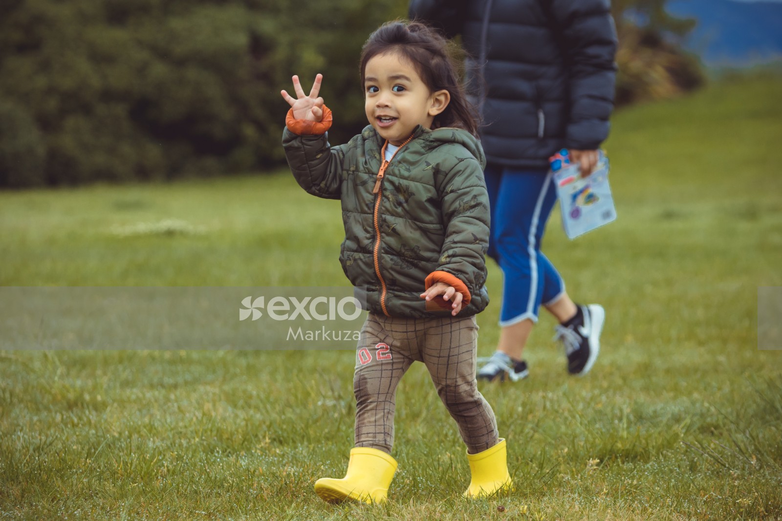Little girl in yellow rain boots making hand sign - Little Dribblers