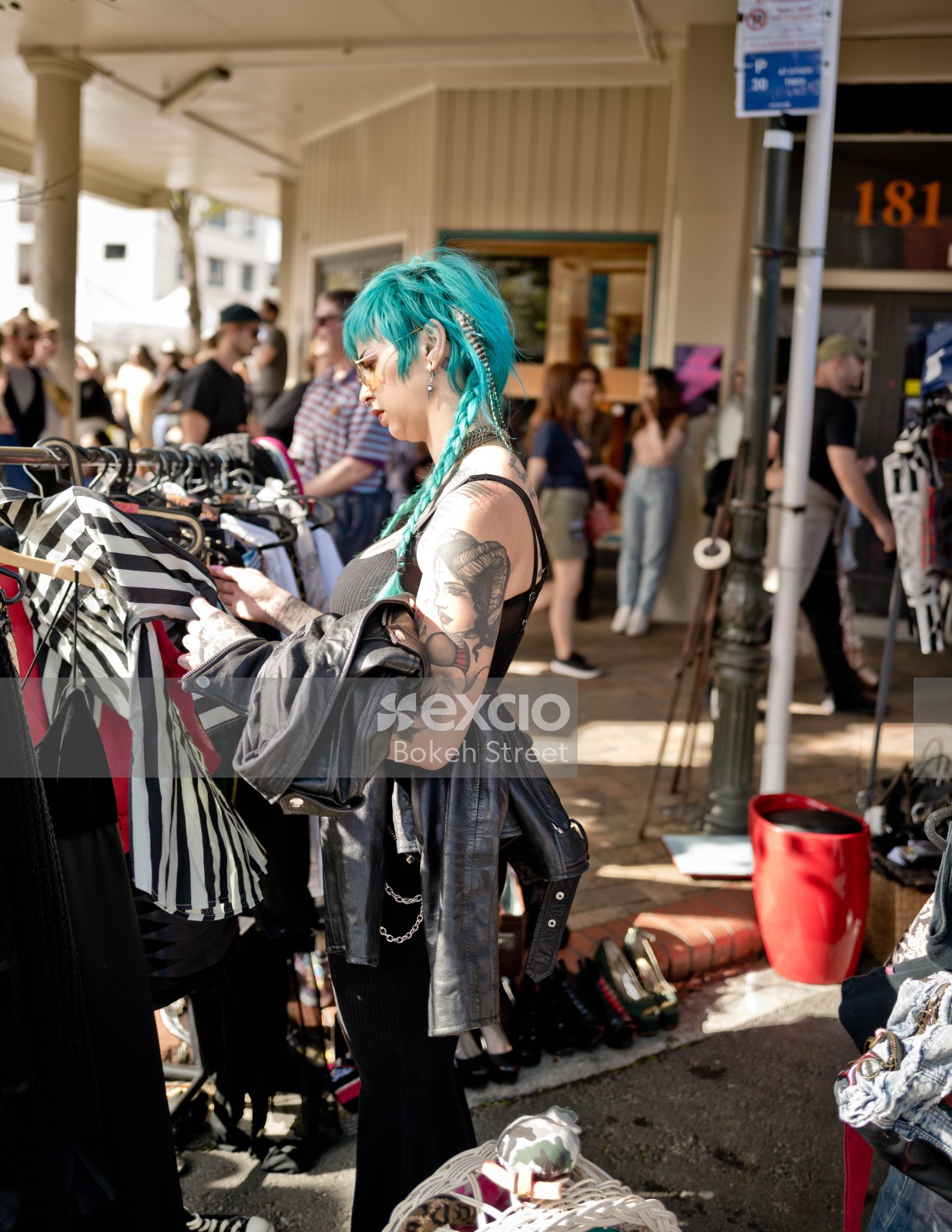 Tattooed cyan haired woman browsing for shirts at a market at Newtown festival 2021