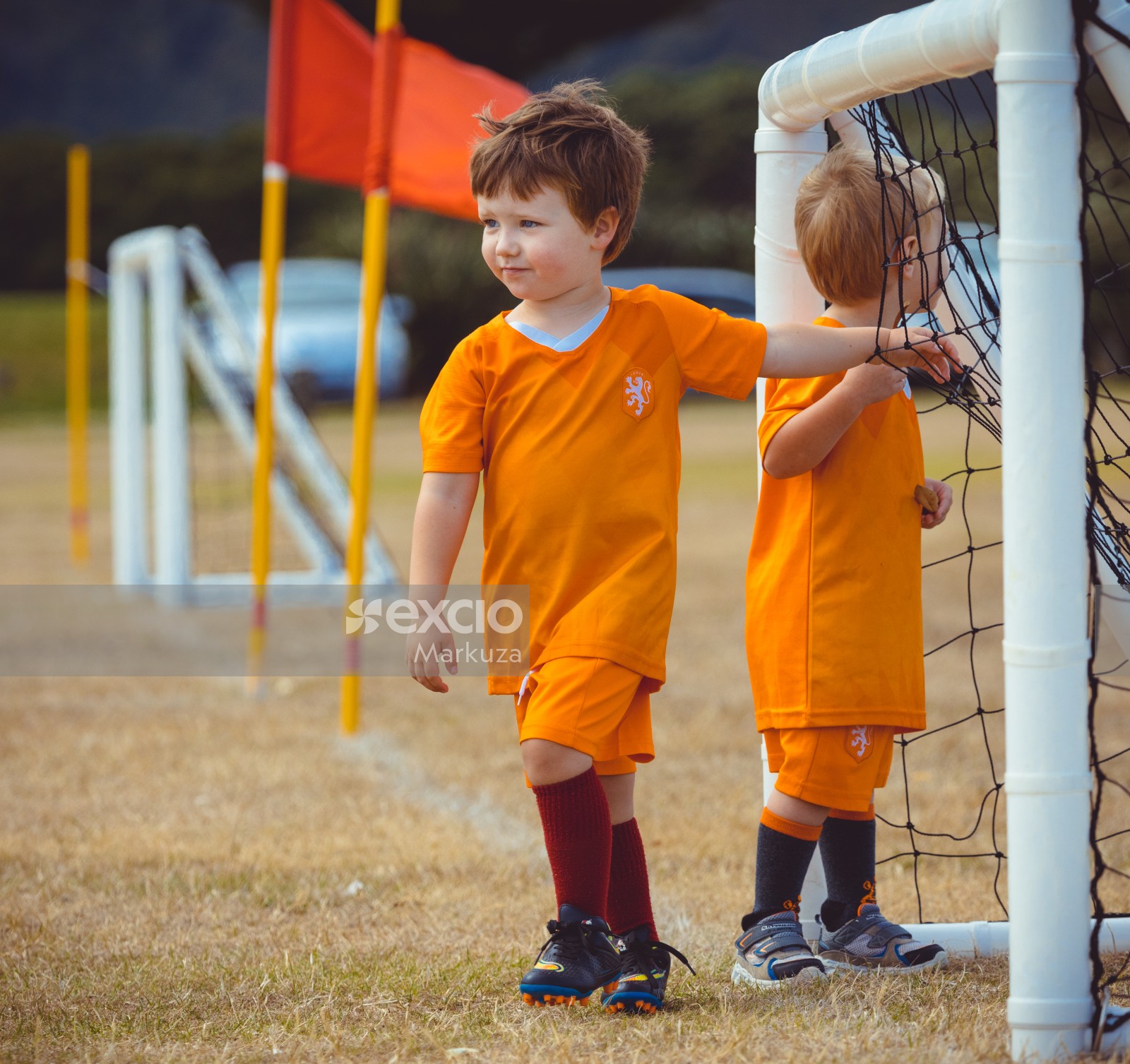 Two boys in Netherlands kit hanging at a football goal post - Little Dribblers