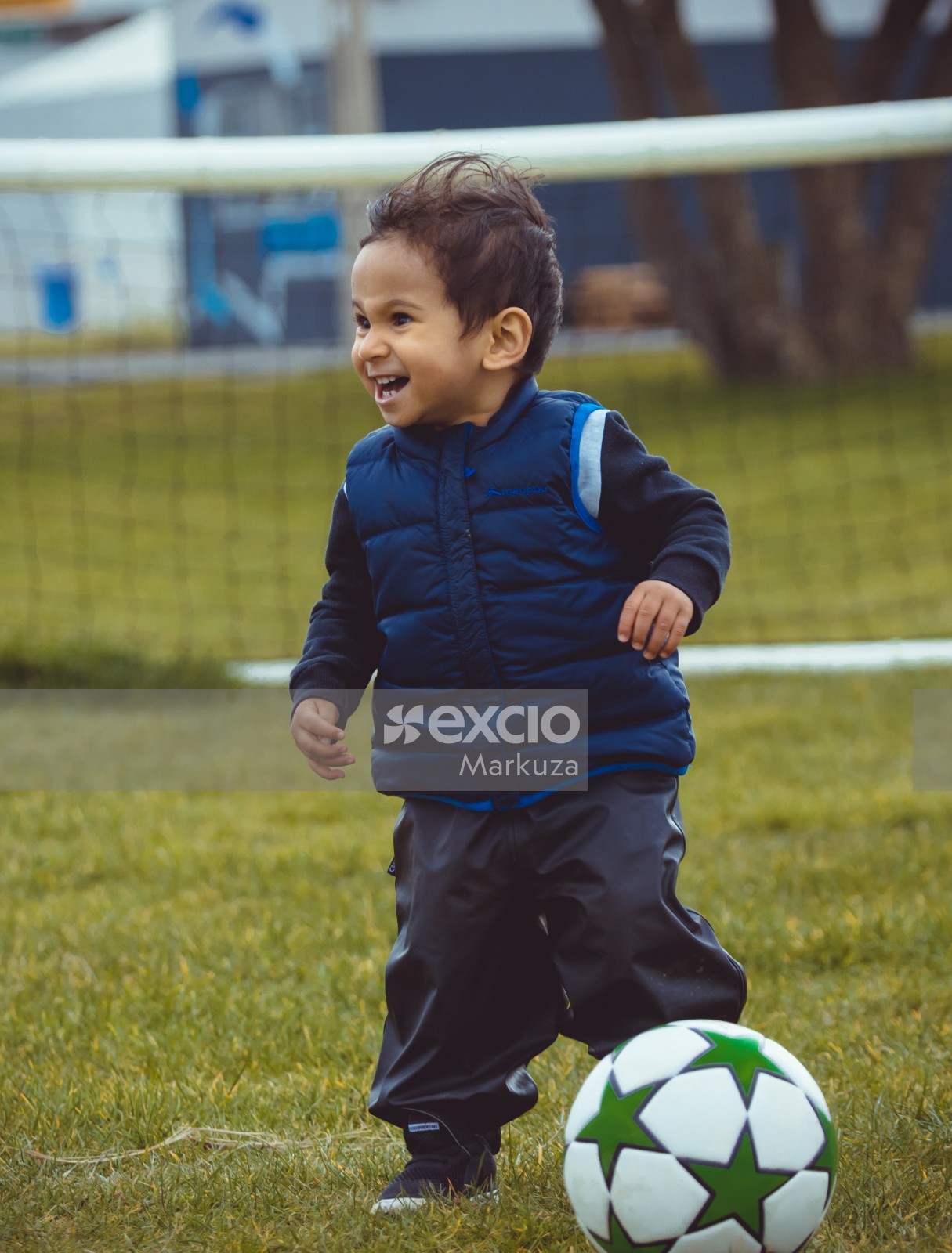 Little boy in a blue sleeveless jacket smiling - Little Dribblers