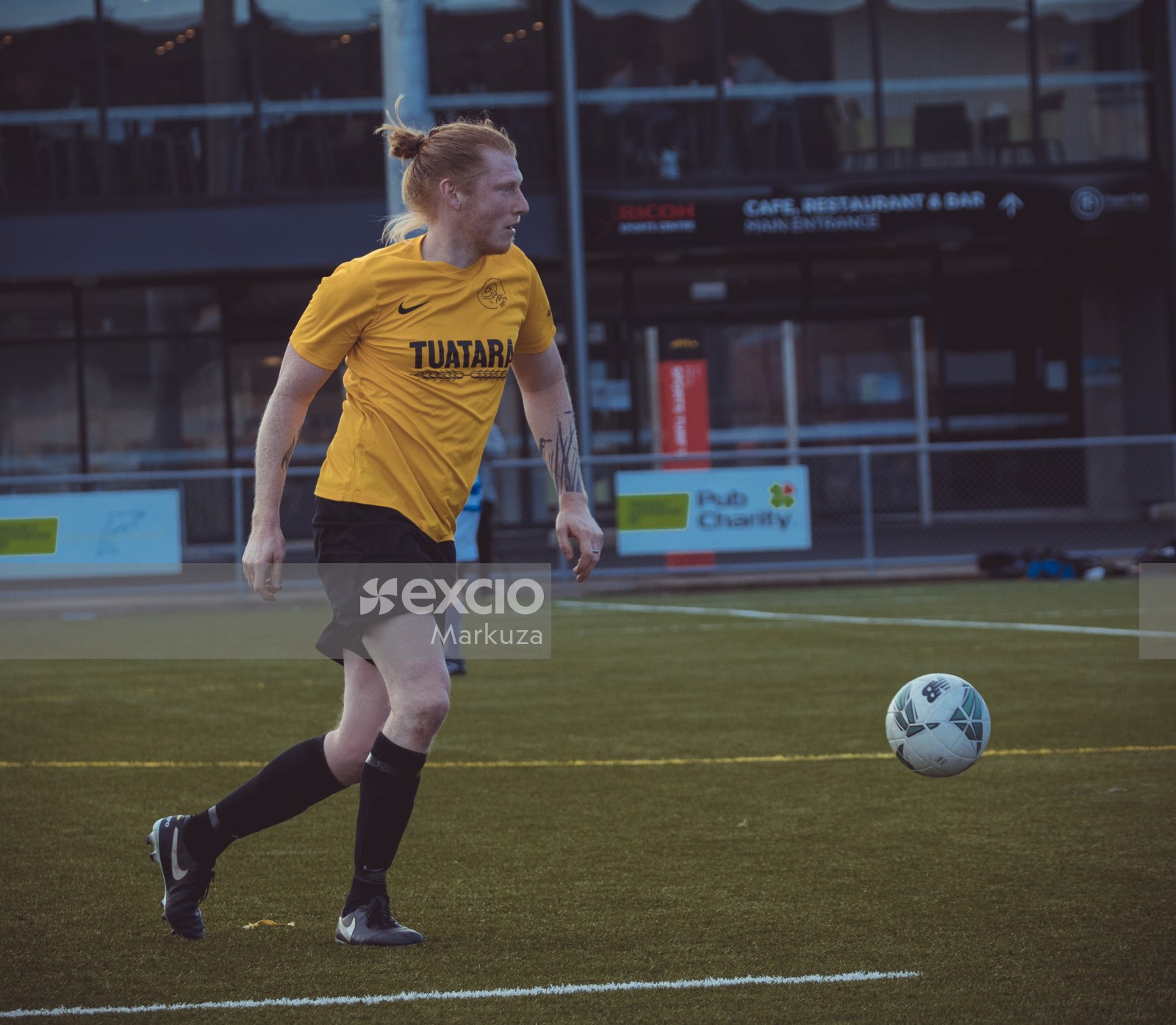 Player in yellow Nike shirt with man bun kicking football - Sports Zone sunday league