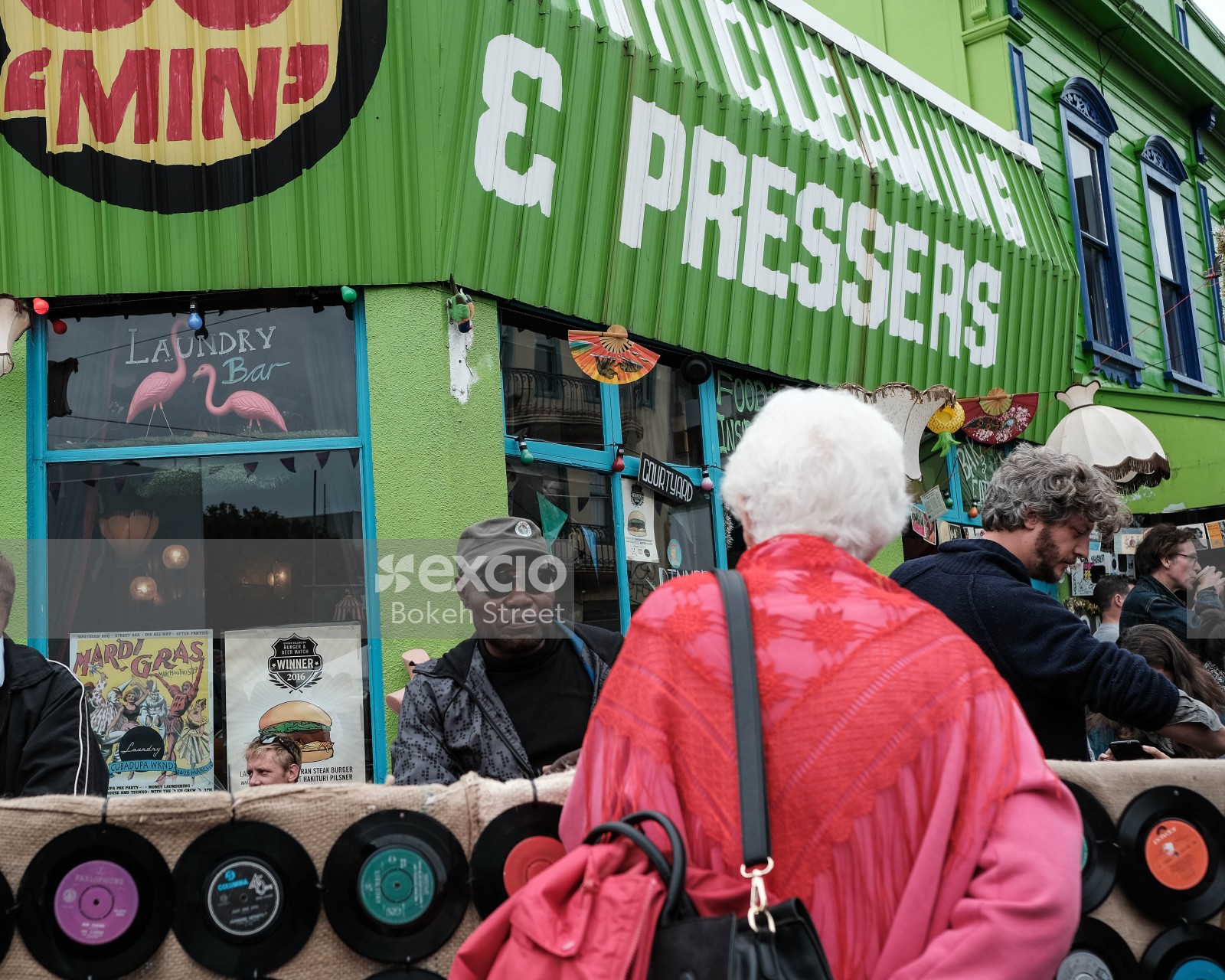 Old woman wearing a pink coat looking at vinyls