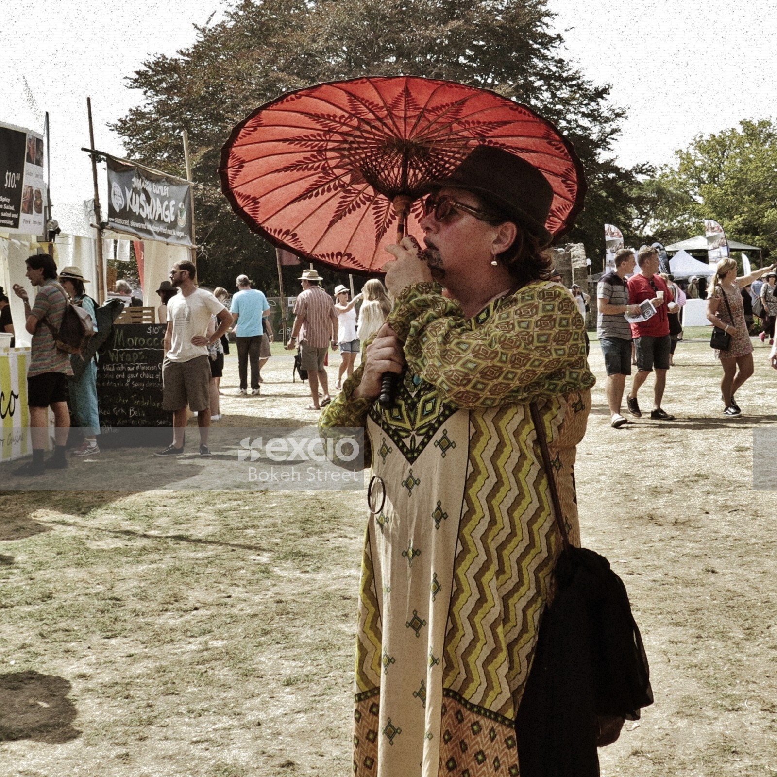 Woman with tribal tattoo holding a red umbrella at WOMAD festival