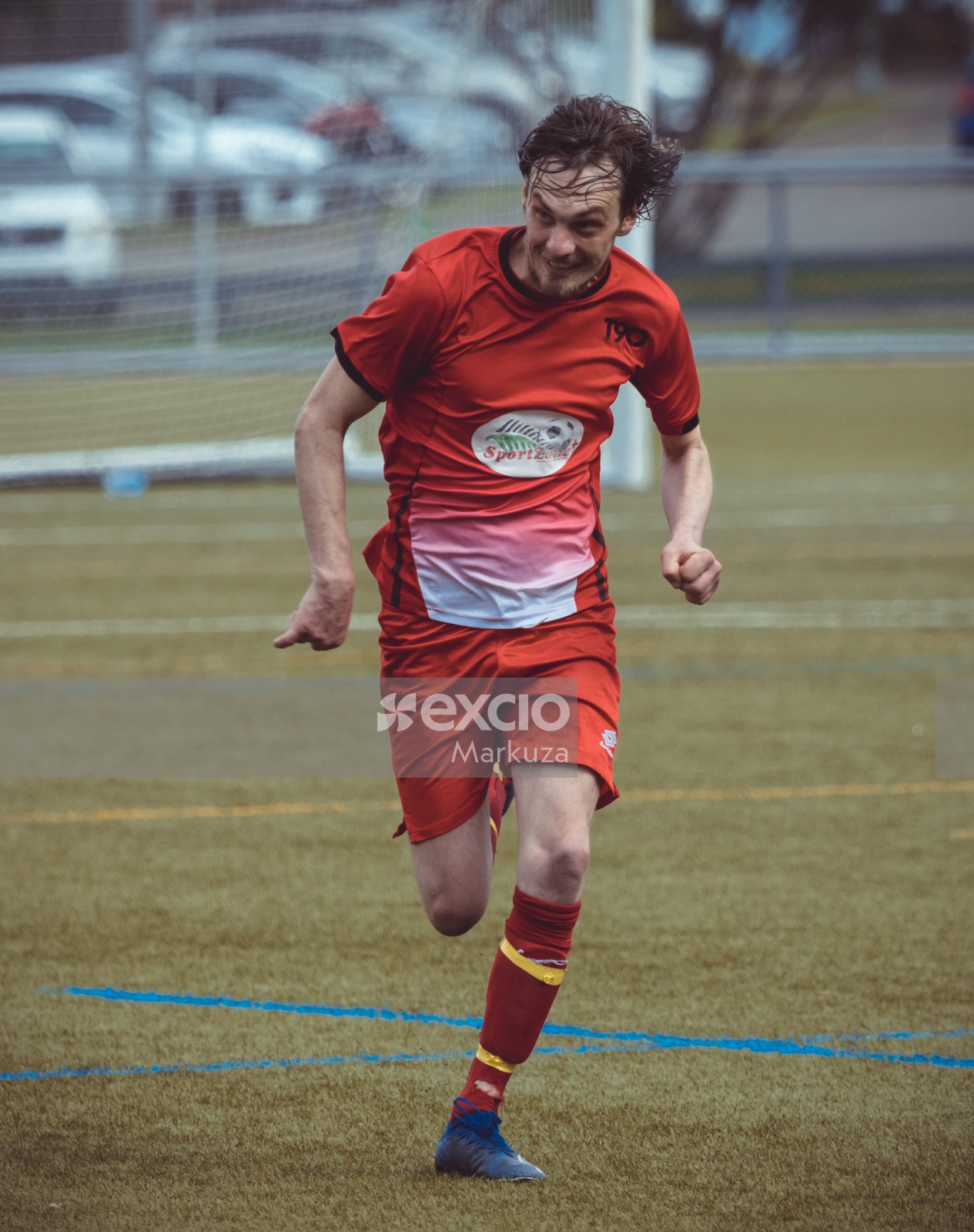 Player in a red kit dashing on the football field - Sports Zone sunday league