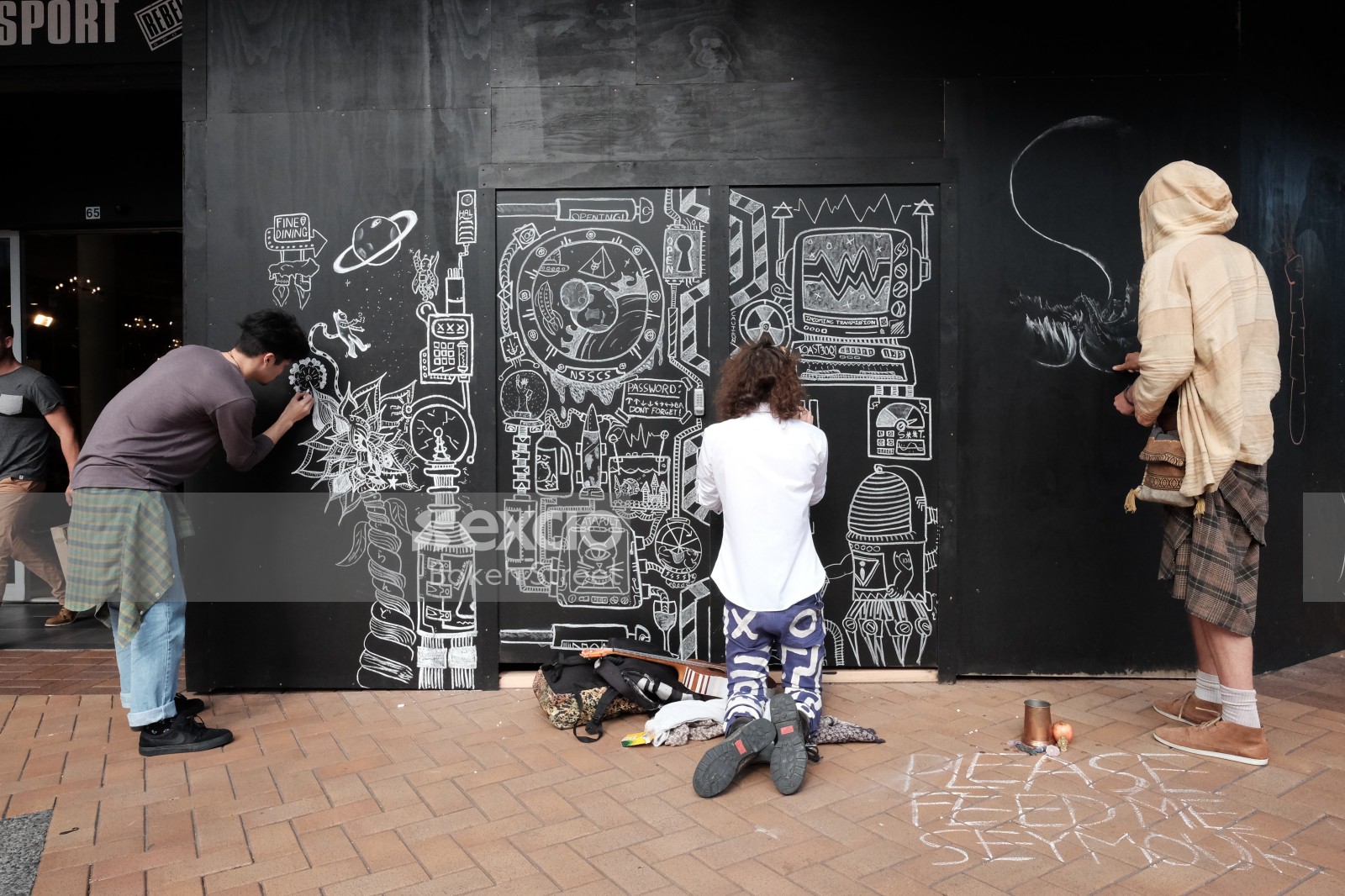 Artists chalk drawing black wall on Cuba Street