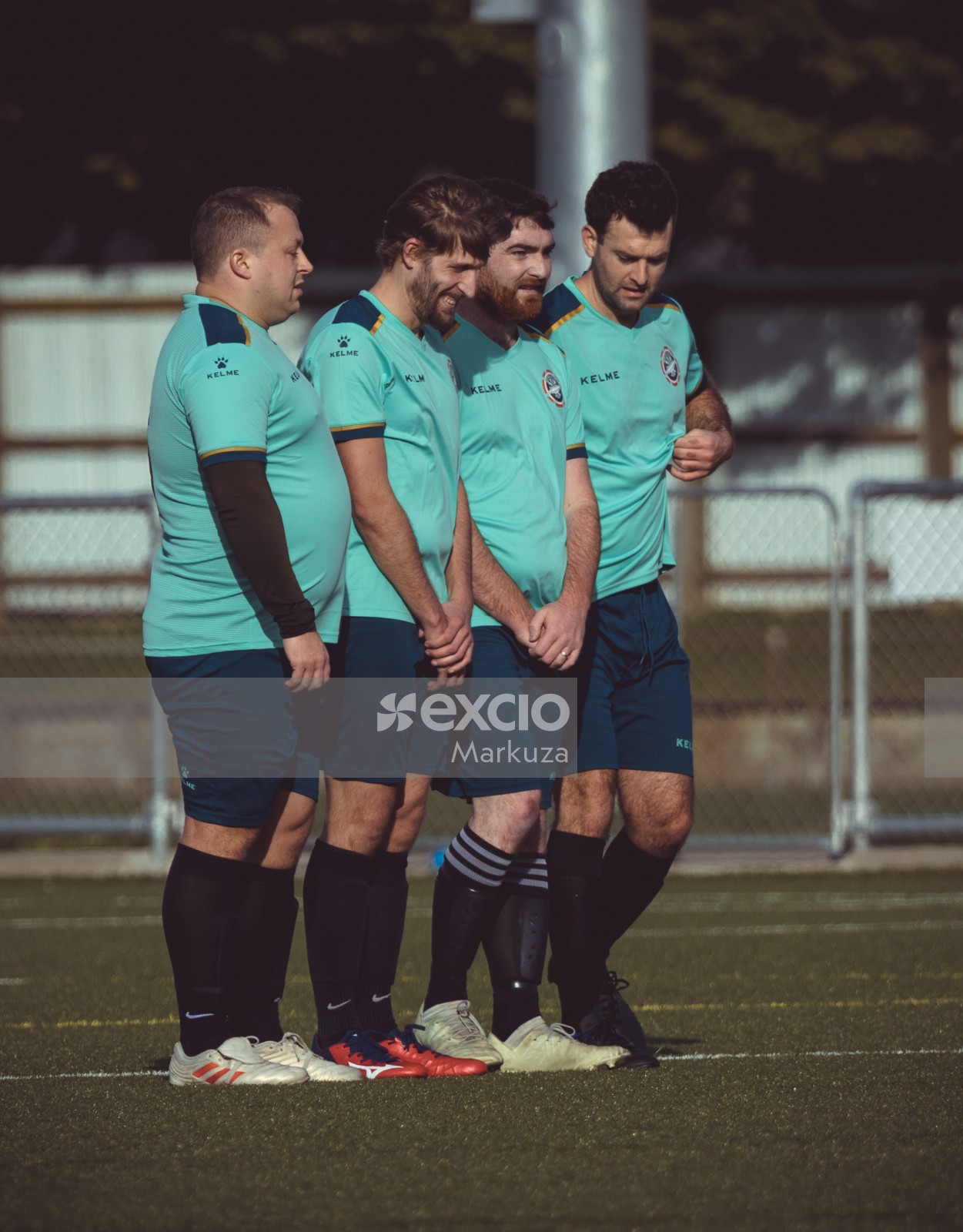 Teammates in turquoise Kelme shirts form defence against freekick