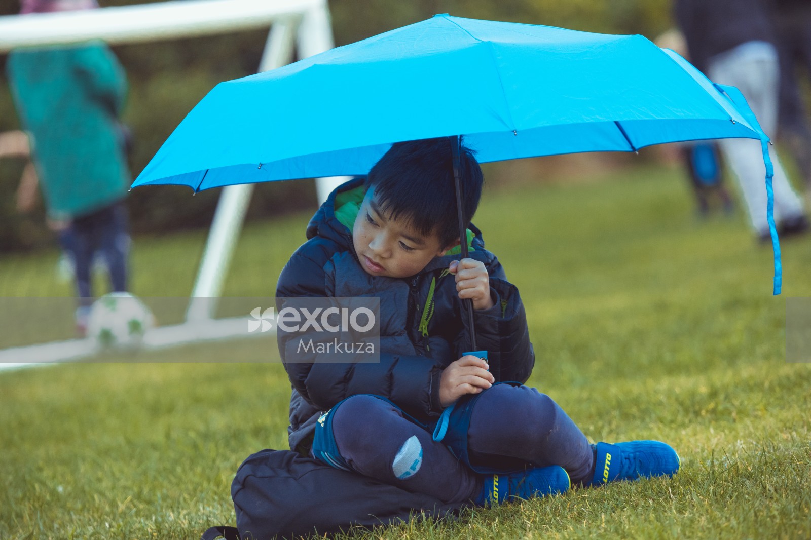 Young boy holding an umbrella over his head at Little Dribblers tournament