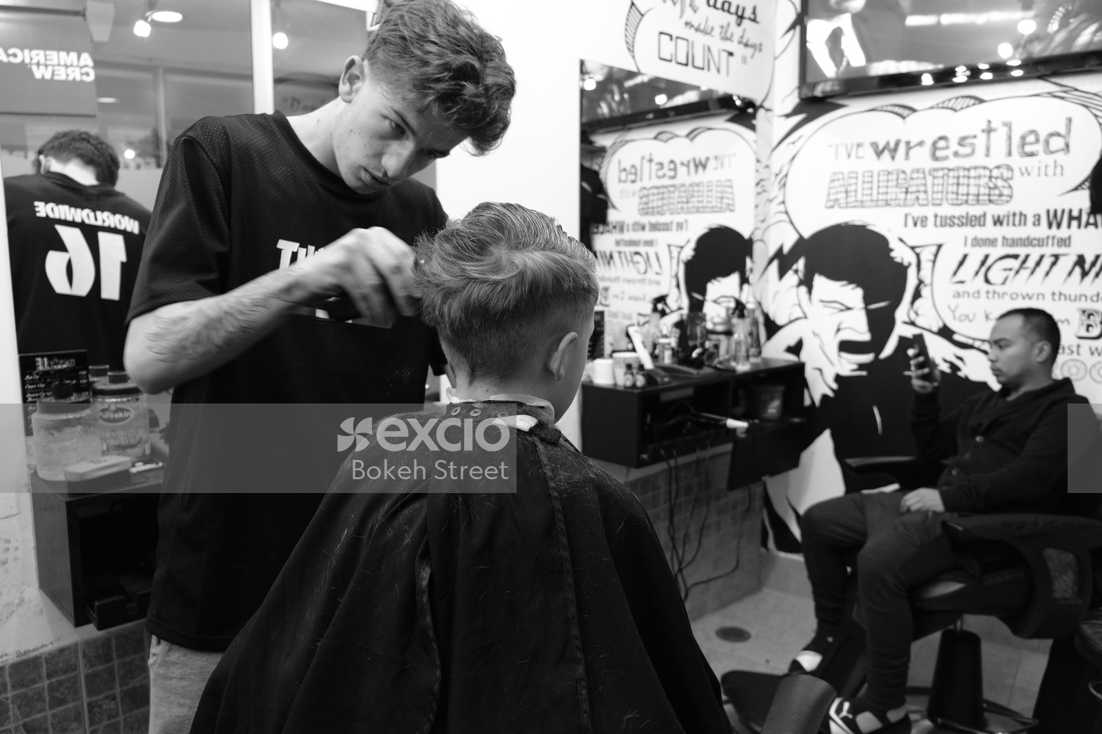 Barber giving a haircut to the boy black and white