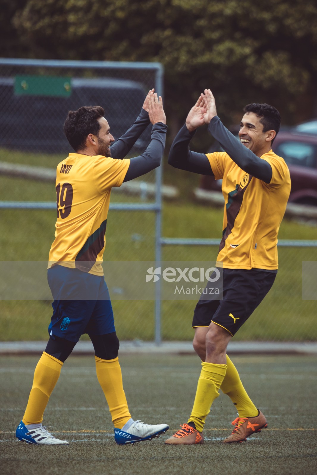 Teammates in yellow shirts double high fiving - Sports Zone sunday league