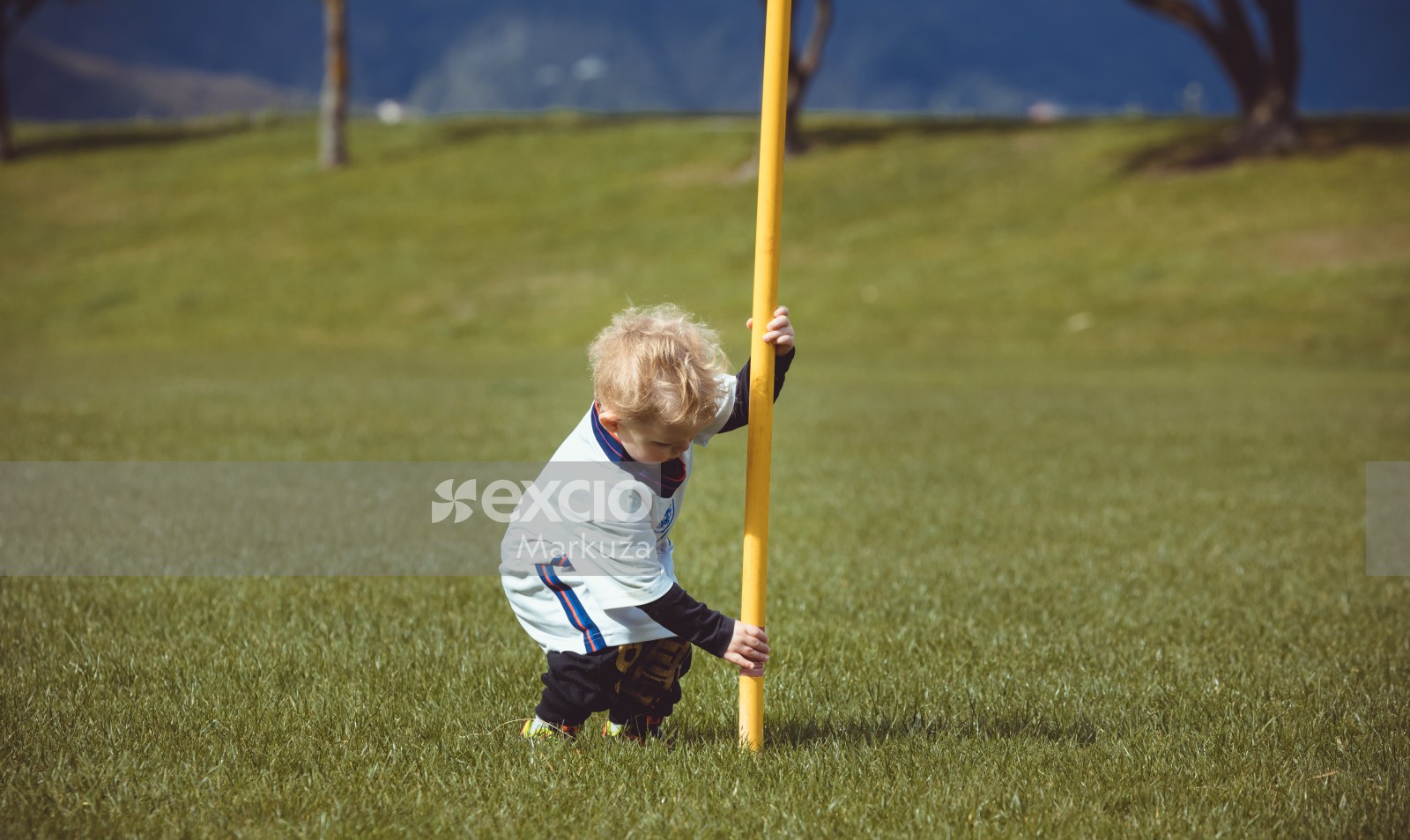 Little blonde haired boy playing with a yellow flag hoist - Little Dribblers