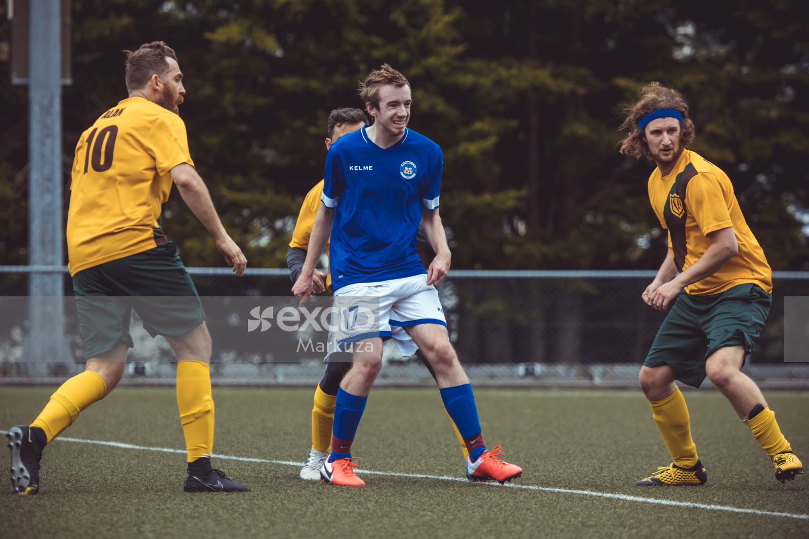 Player in blue shirt orange cleats surrounded by opposing team - Sports Zone sunday league