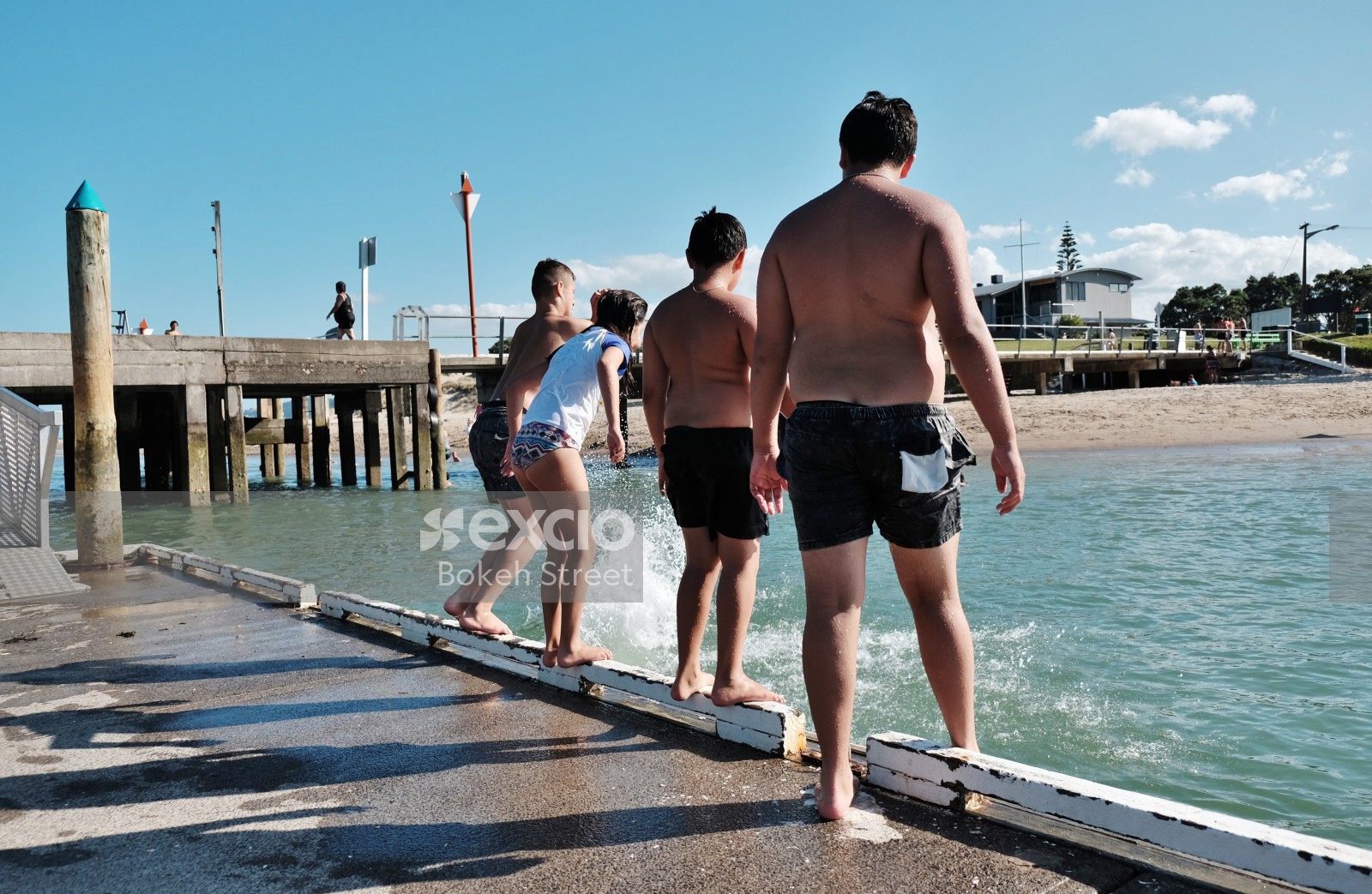 Boys and a girl jumping off a pier