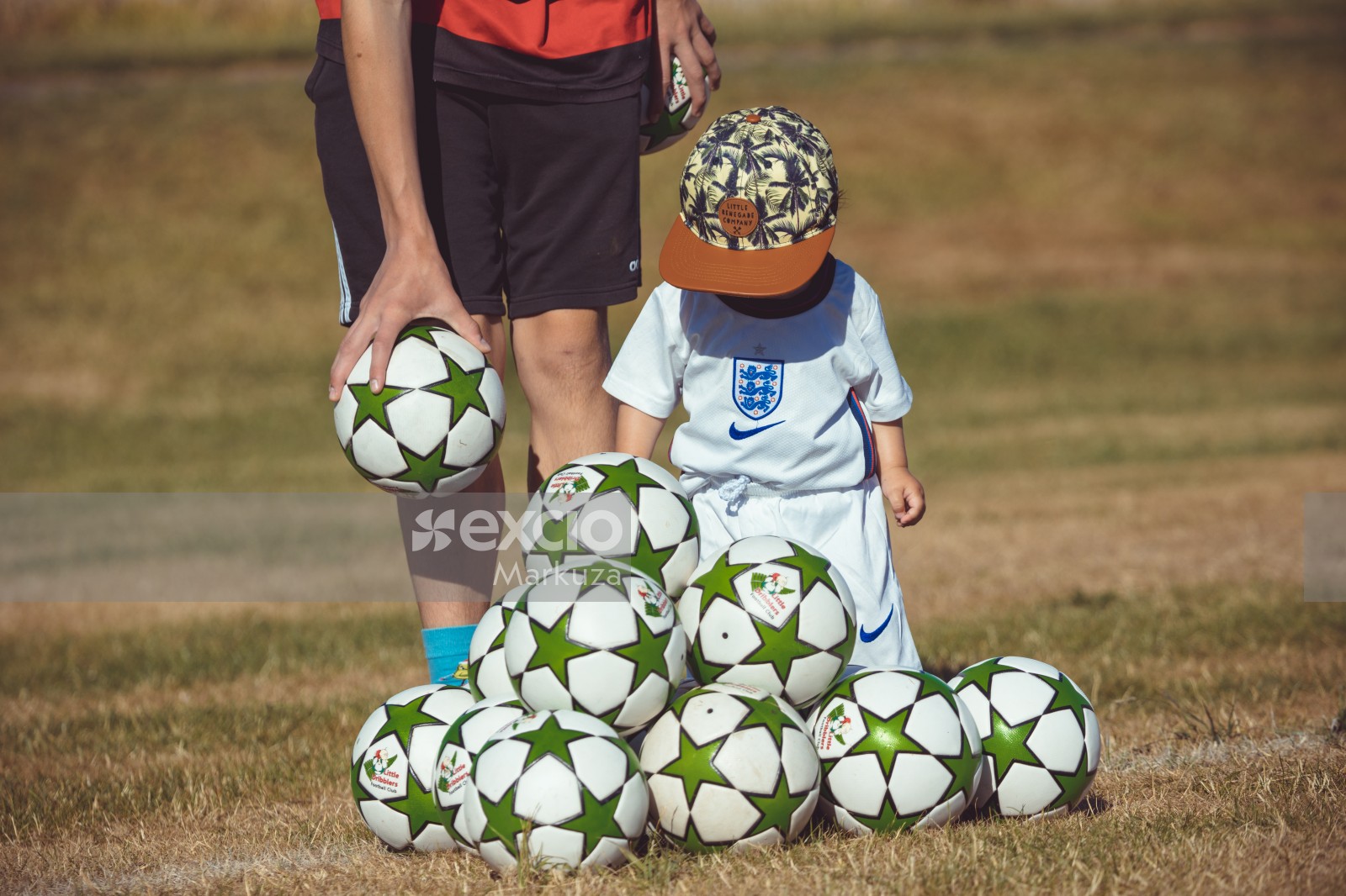 Kid with a pile of footballs at Little Dribblers