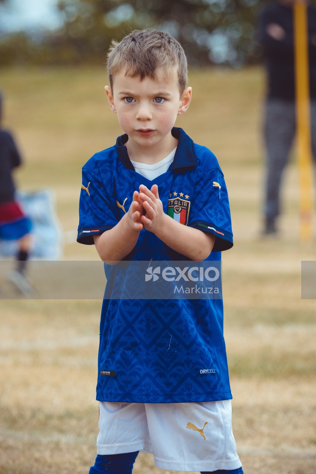 Little blue eyed kid clapping in Italia kit at Little Dribblers soccer game