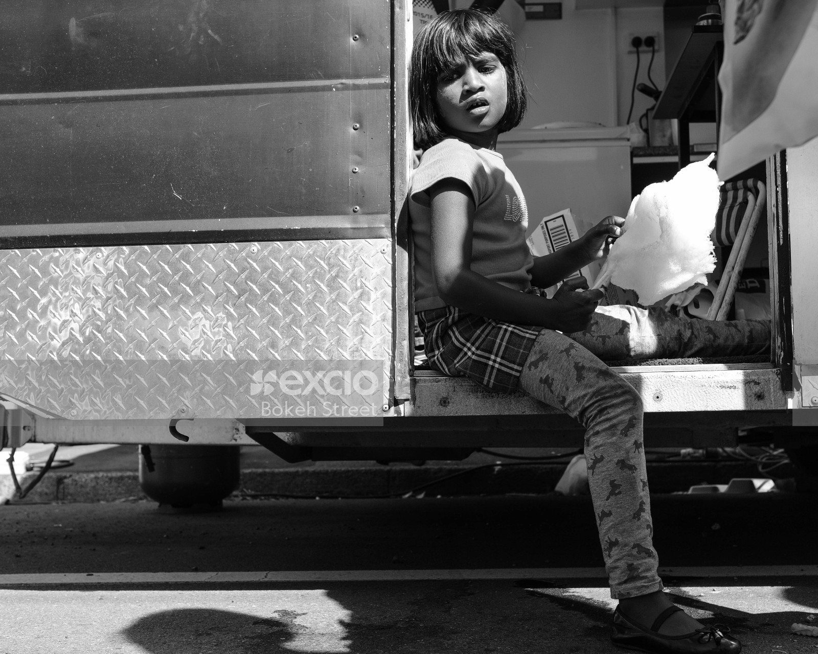 Child sitting in a food truck eating cotton candy black and white