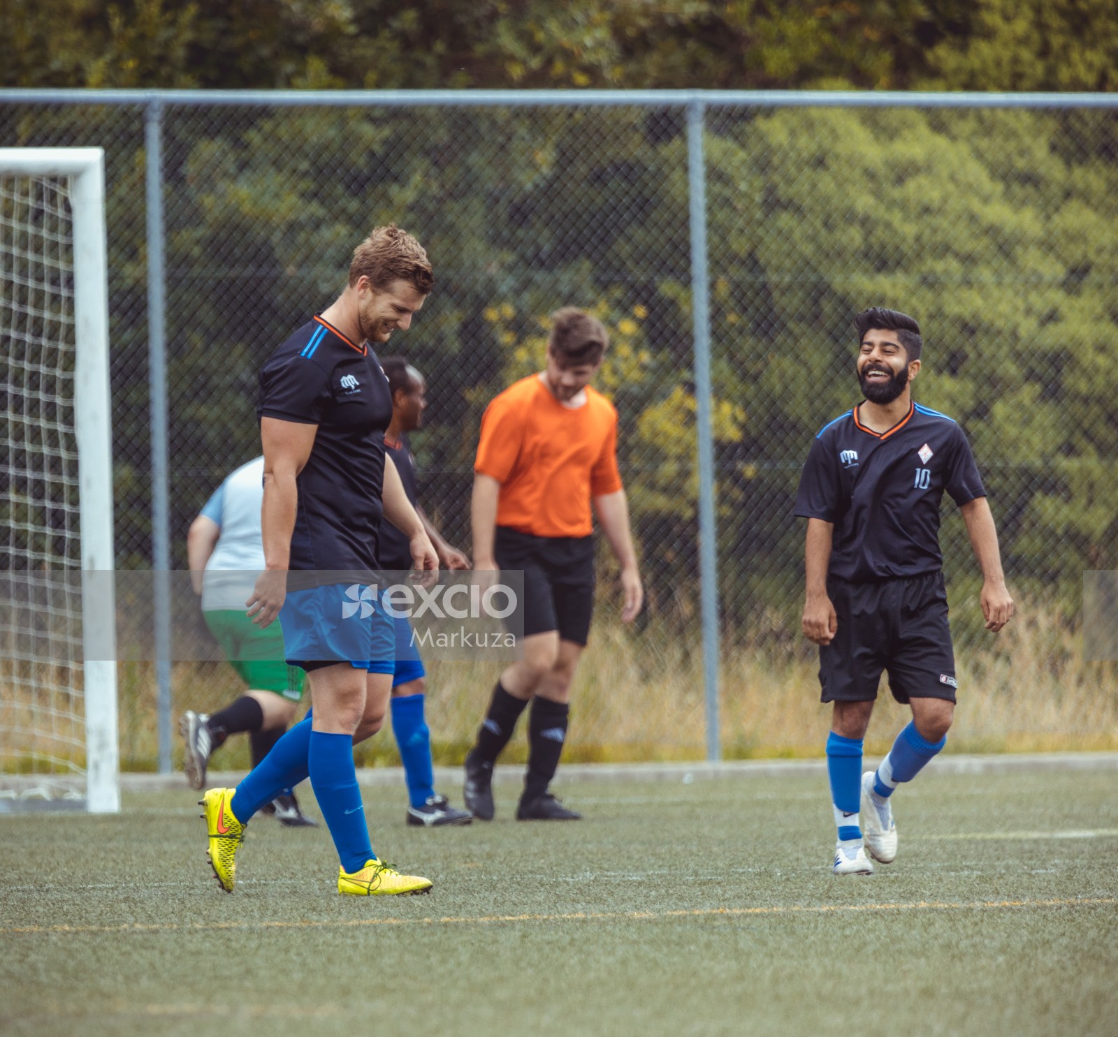 Teammates in black shirts giggling in the field - Sports Zone sunday league