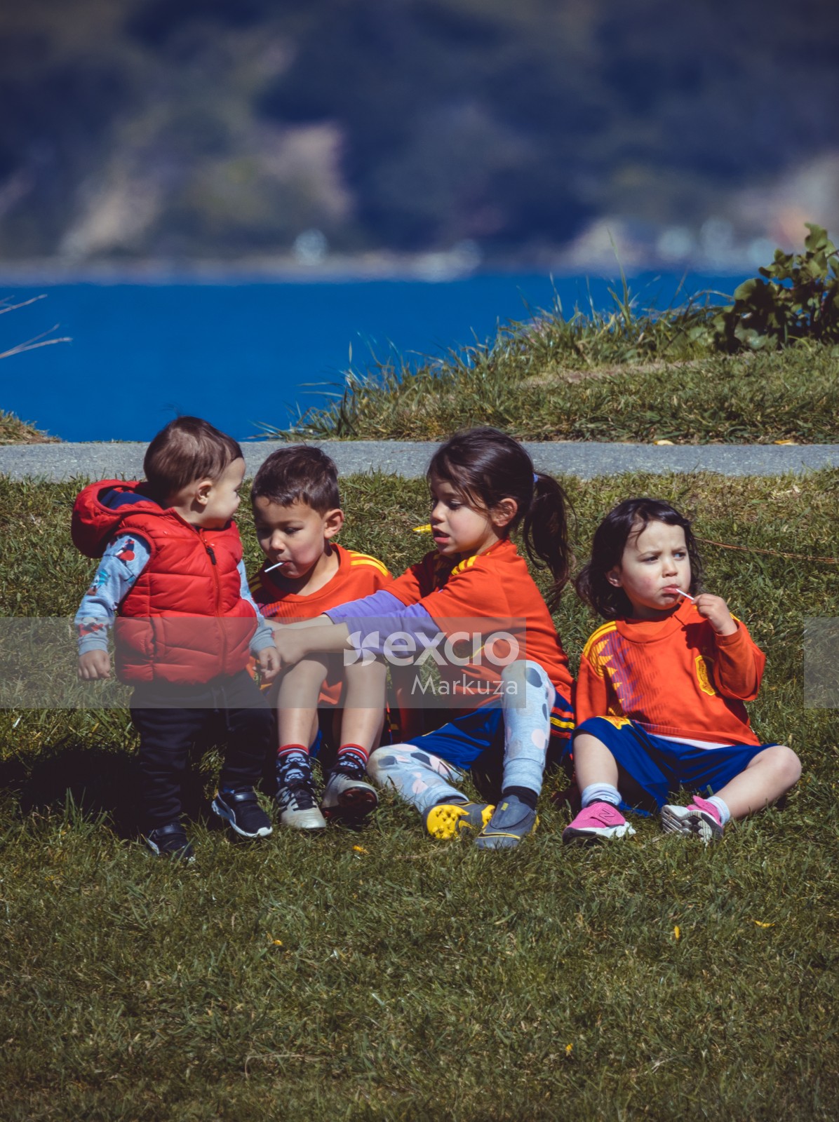 Four little kids sitting on the grass eating candy - Little Dribblers