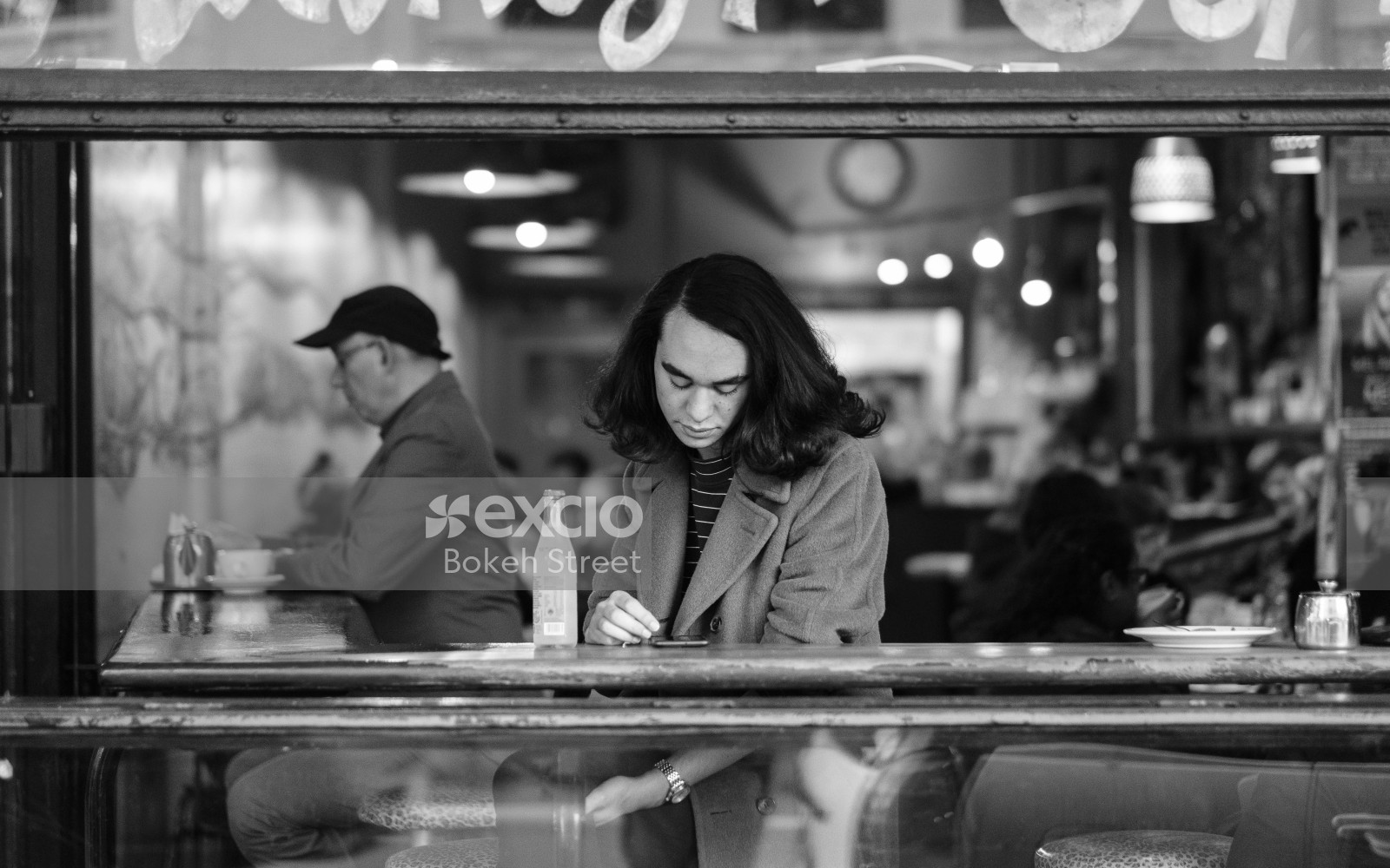 Woman looking at her phone in a cafe black and white