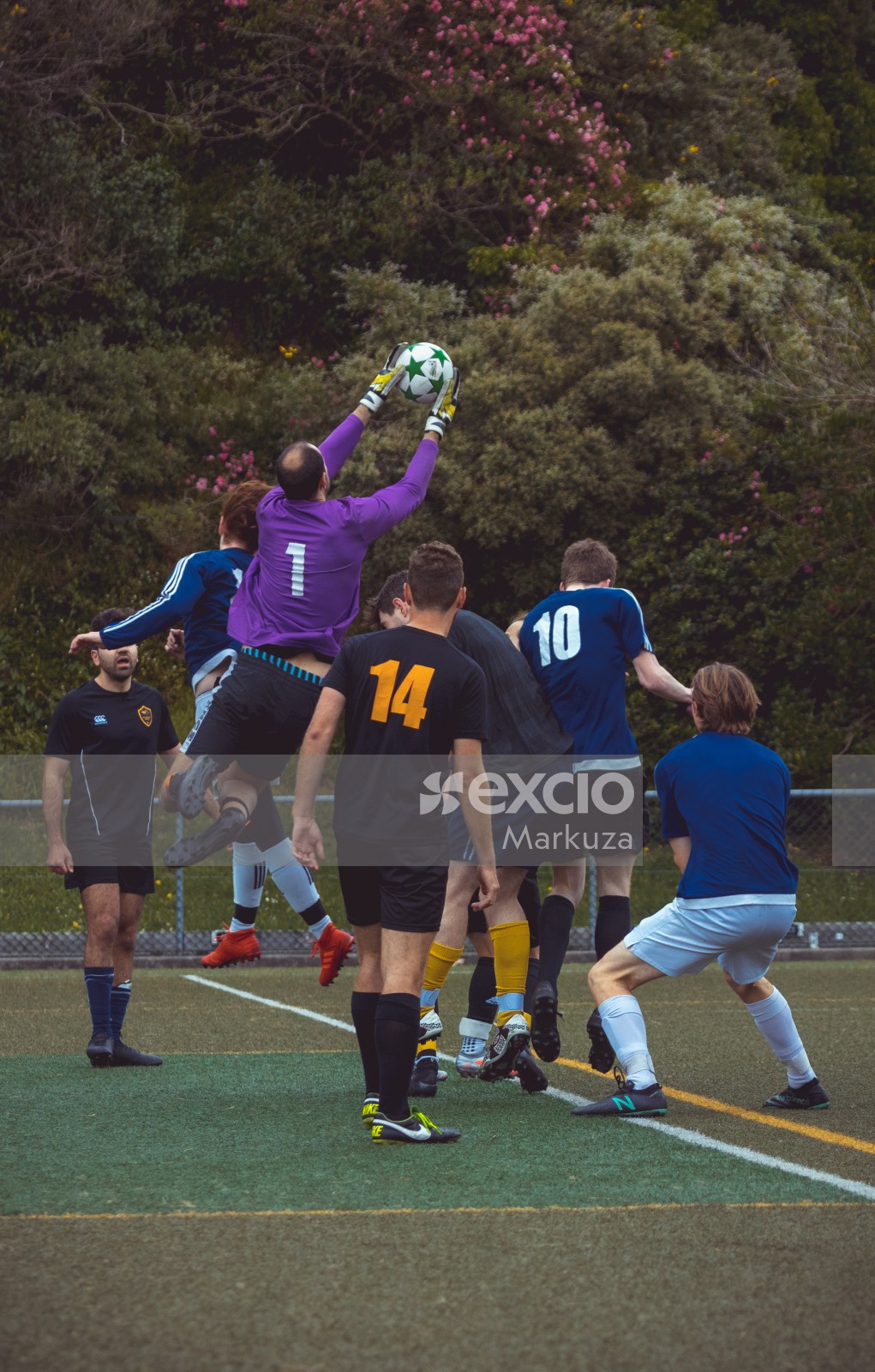 Bald goalkeeper in purple shirt catches ball midair - Sports Zone sunday league