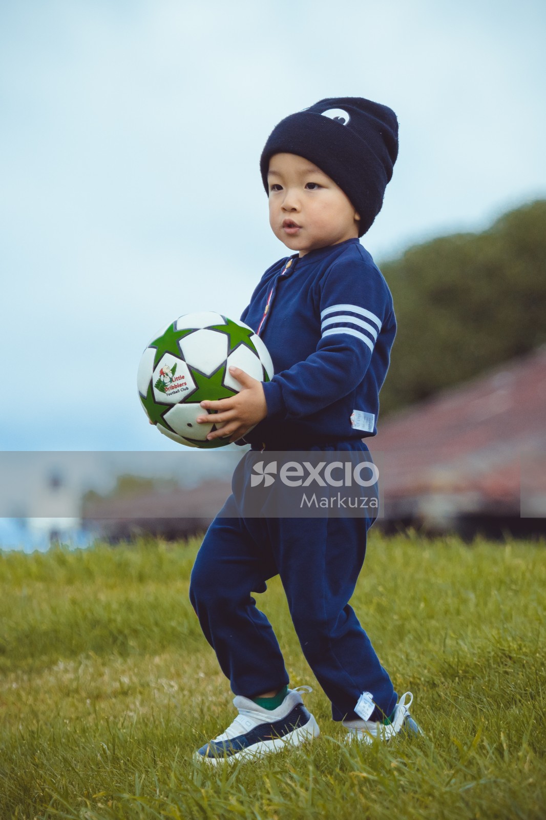 Little boy in blue jogging suit carrying a football - Little Dribblers