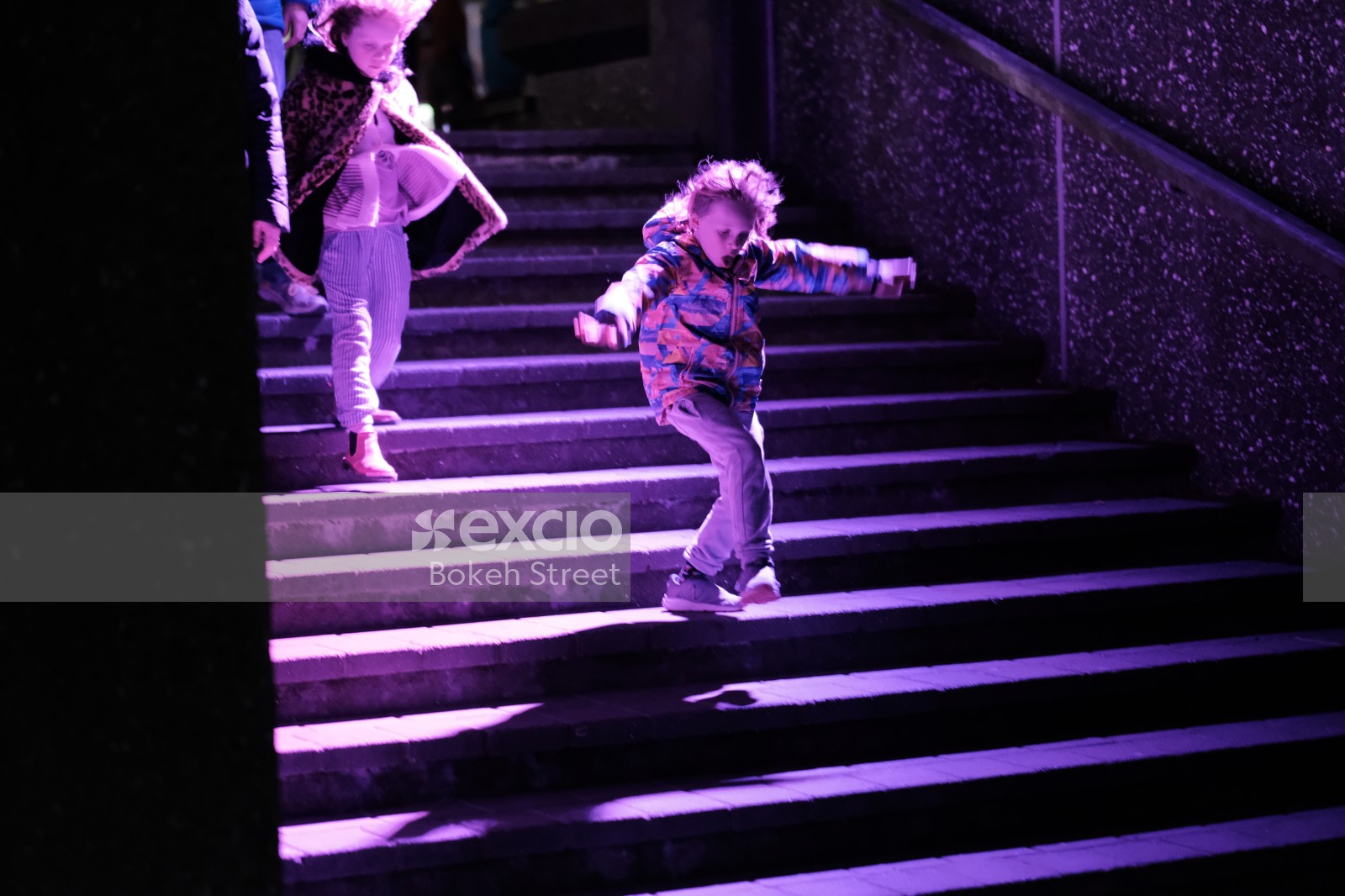 Little girls walking on purple lit stairs 
