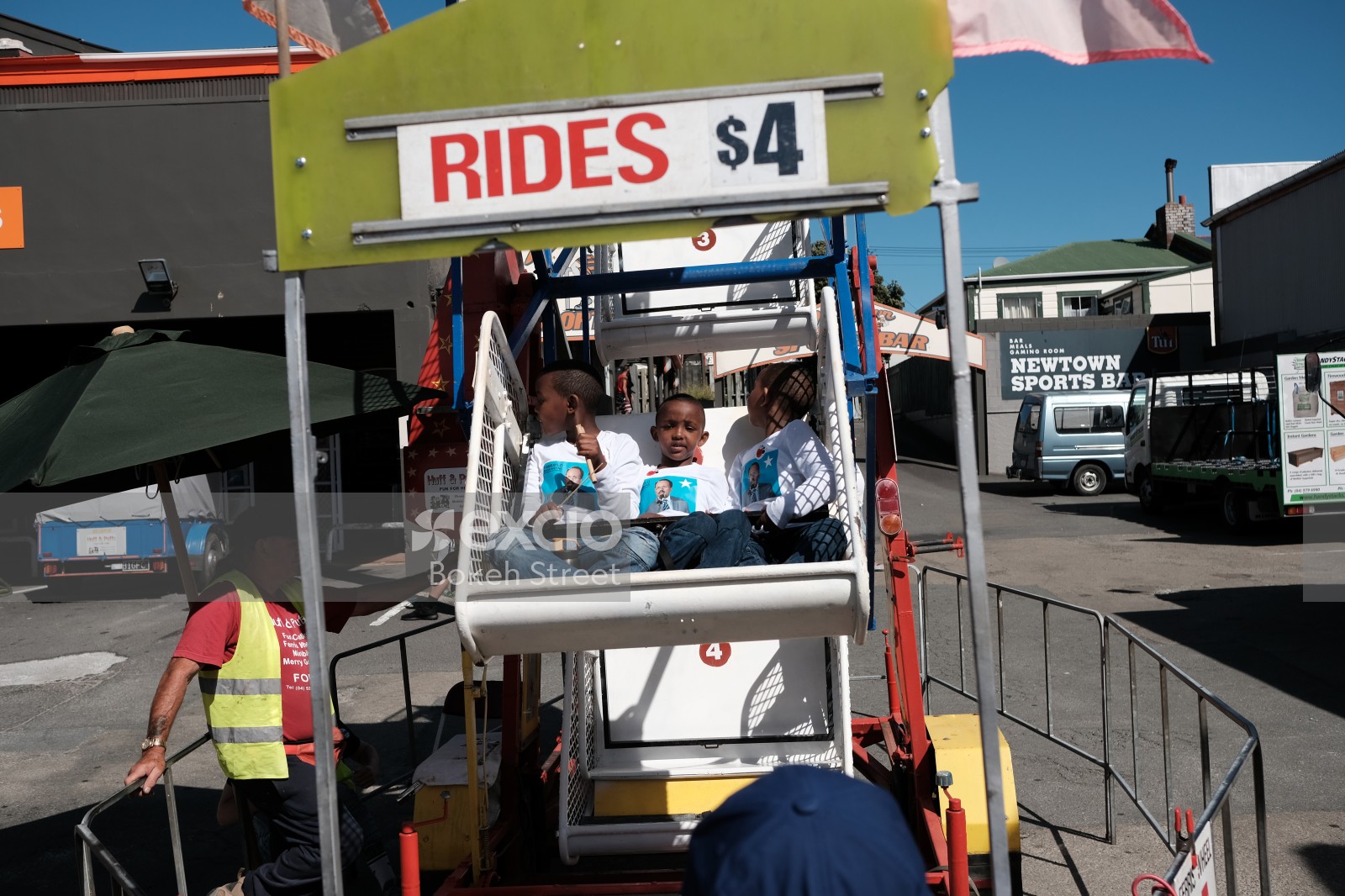 Three kids on a mini ferris wheel at Newtown festival 2021