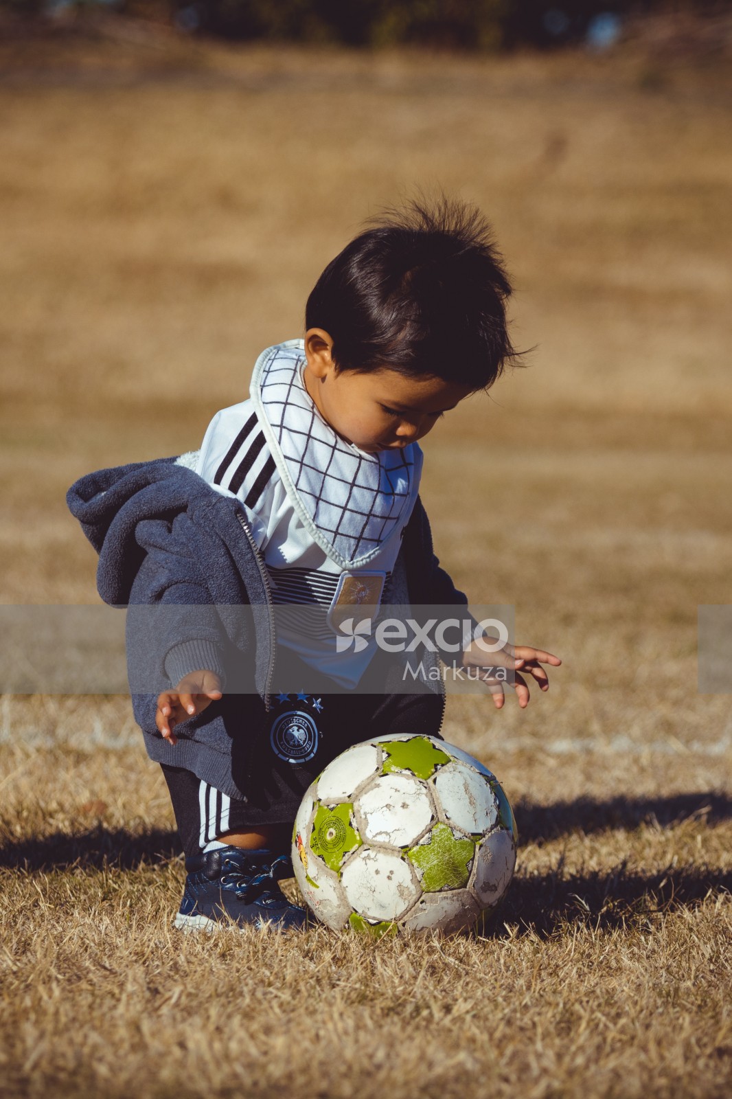 Boy wearing German kit and check bib playing with a football - Little Dribblers