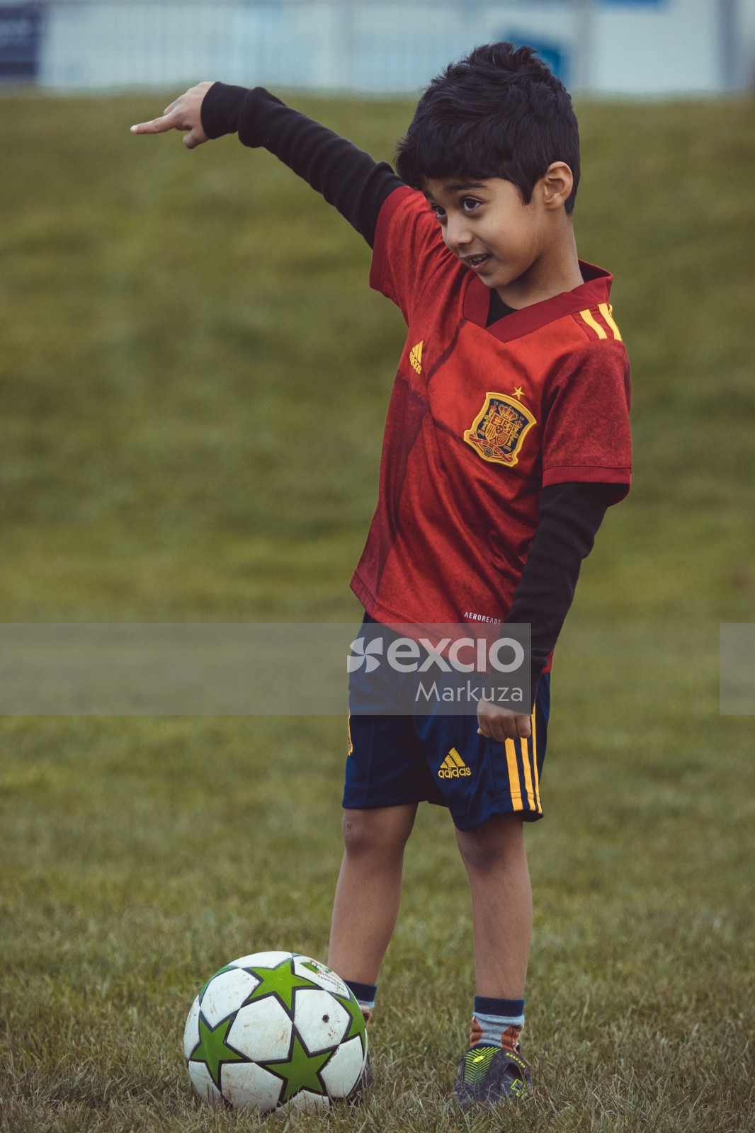 Kid in red shirt and blue shorts with a football