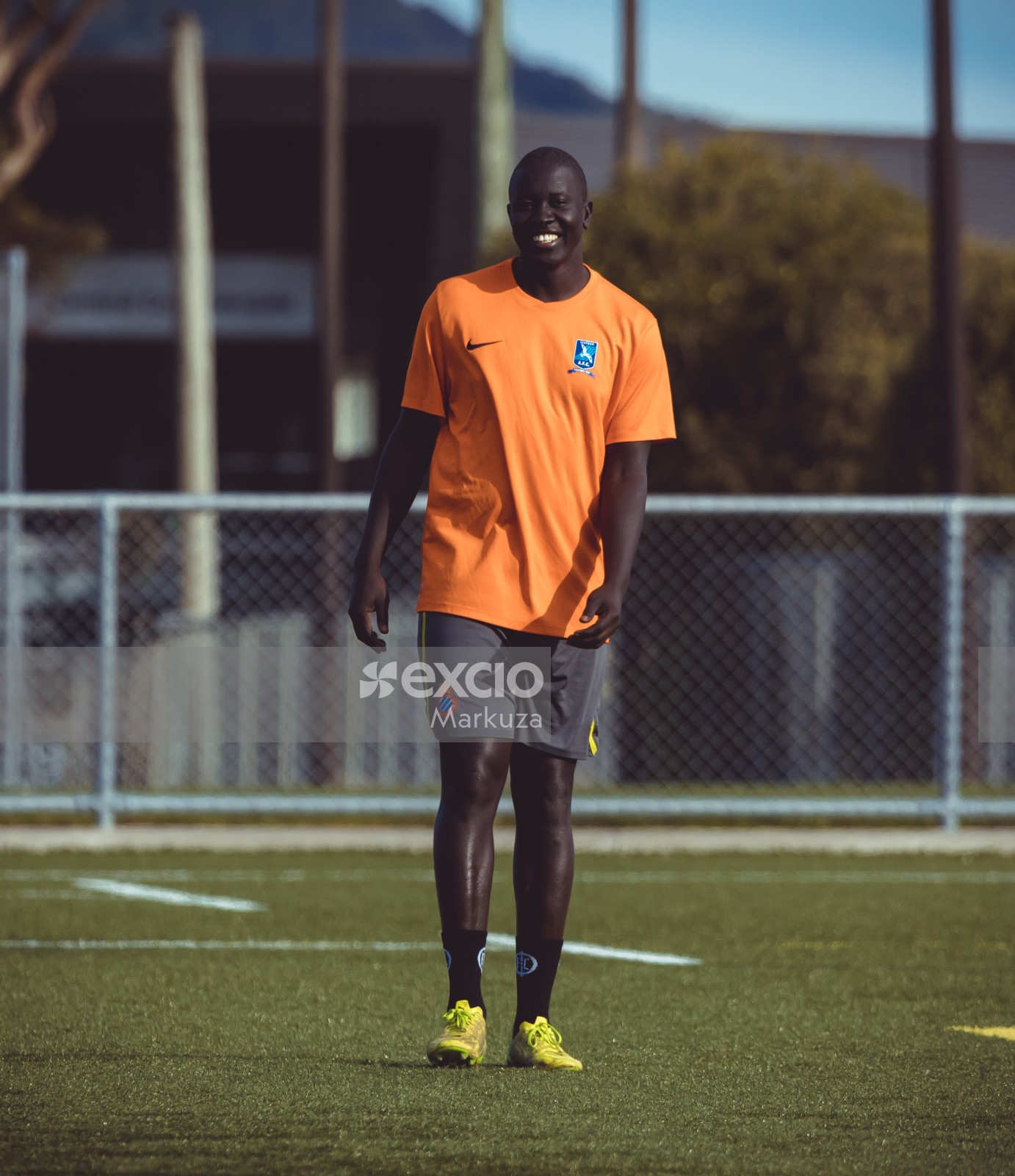 Tall dark skinned football player in orange Nike shirt