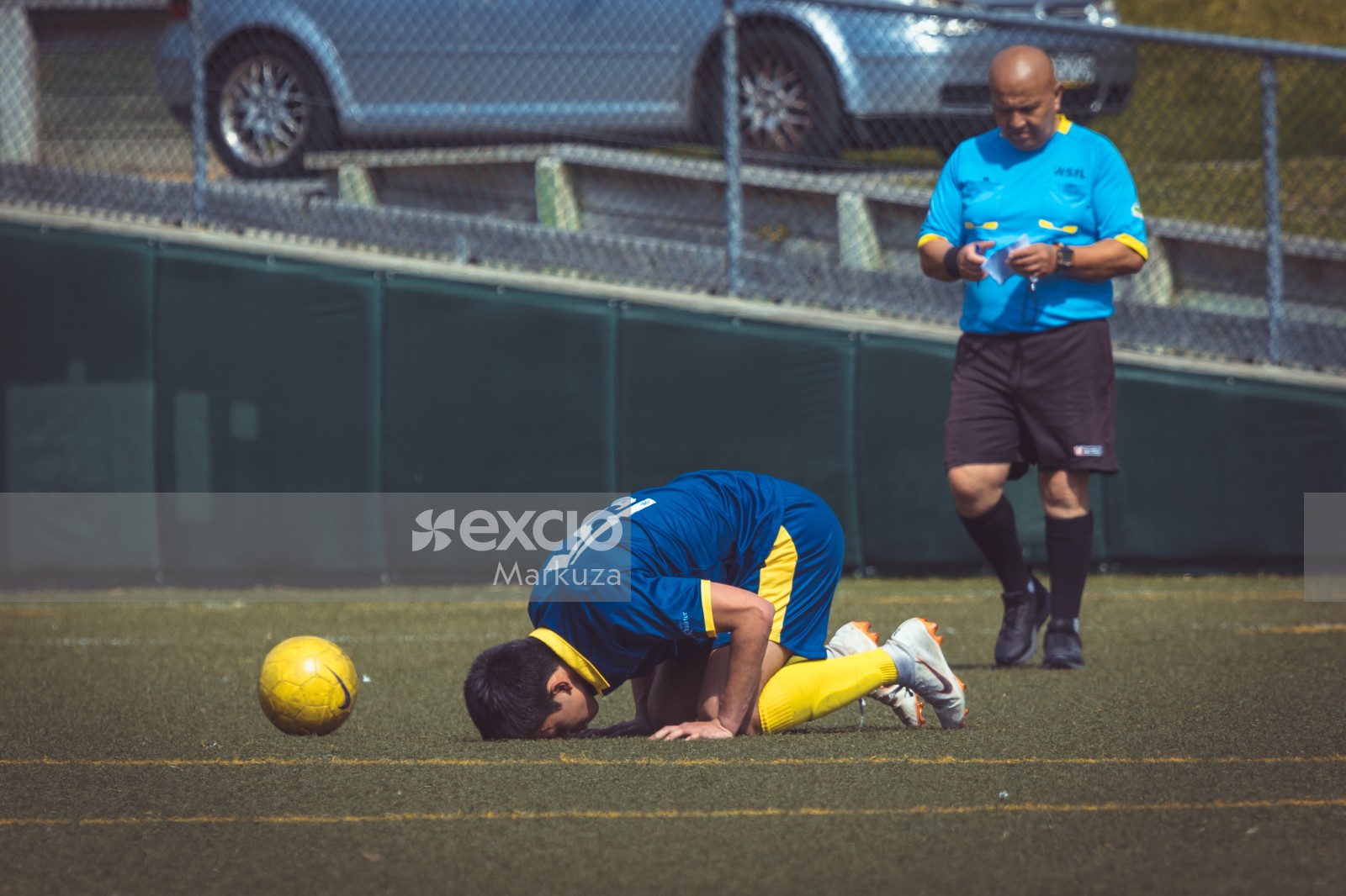 Footballer bow down to earth next to yellow Nike football - Sports Zone sunday league