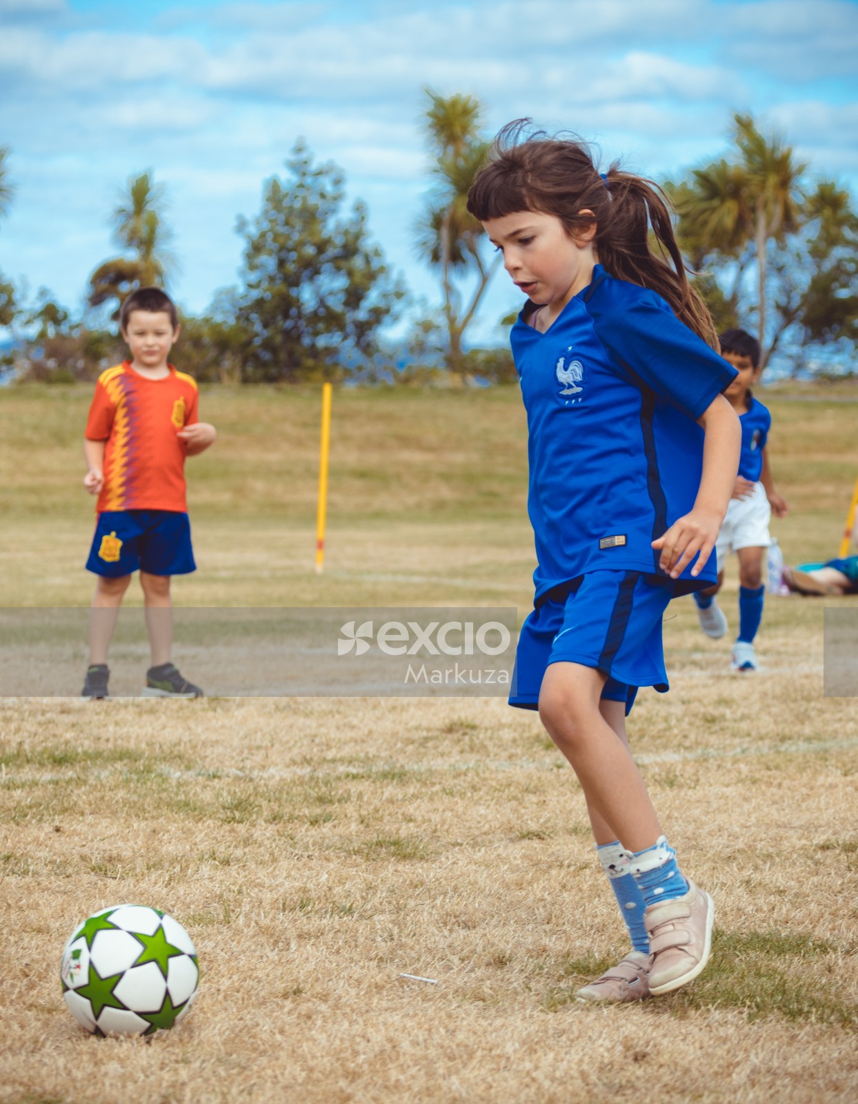 Girl in French kit playing football at Little Dribblers football match