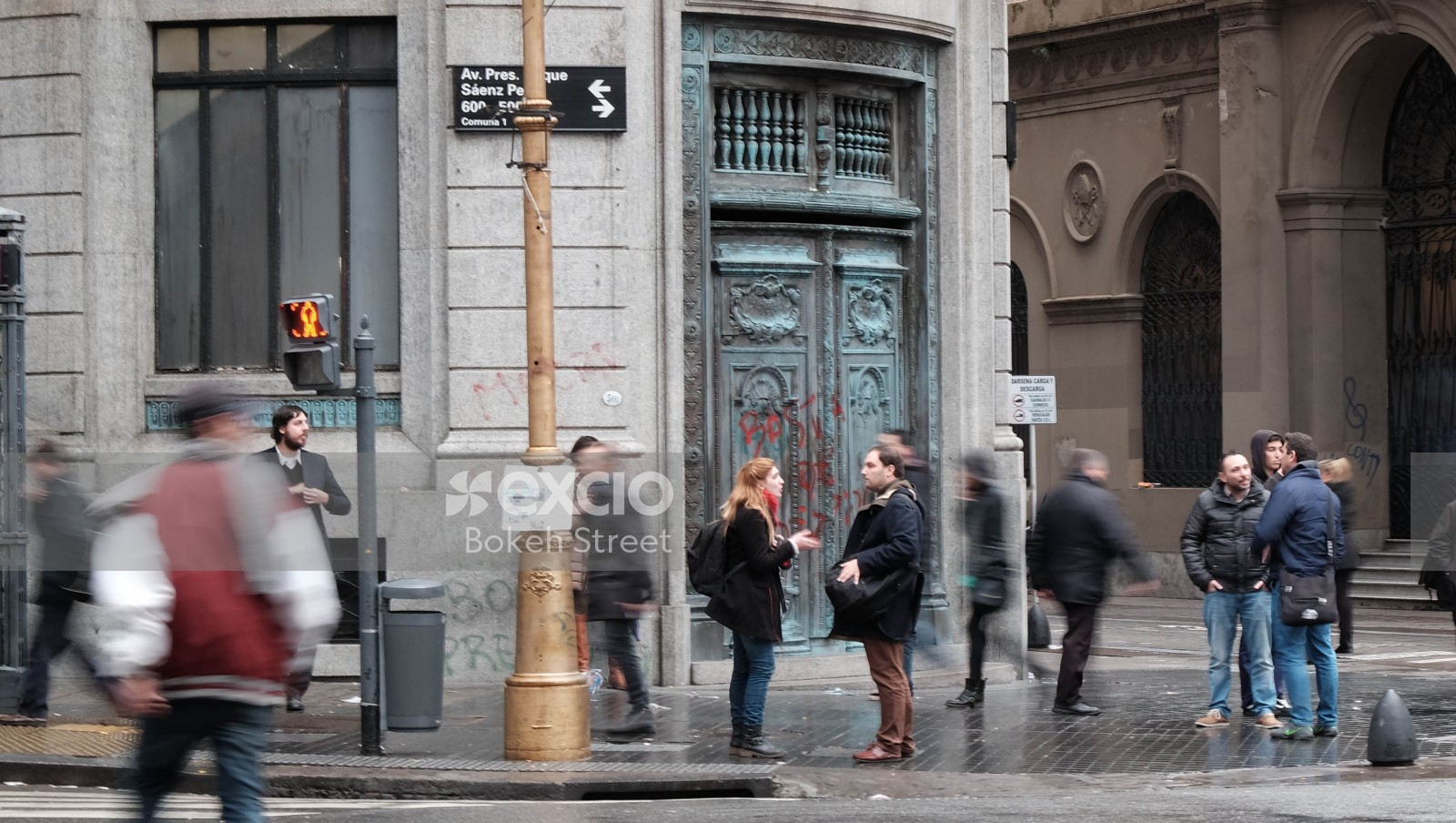 People in the street in front of a big building with carved door golden pole