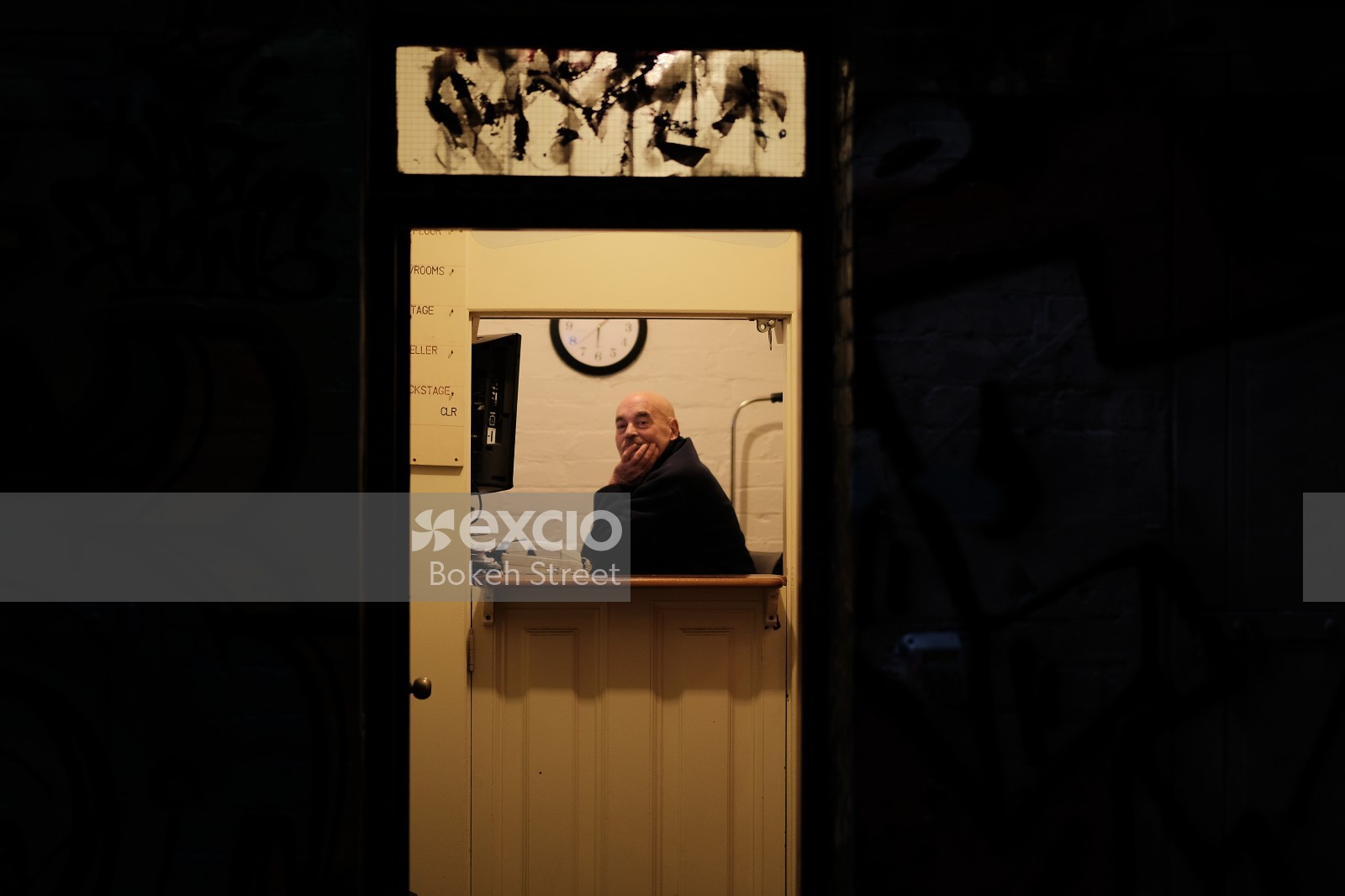 Bald man sitting inside a building with split door