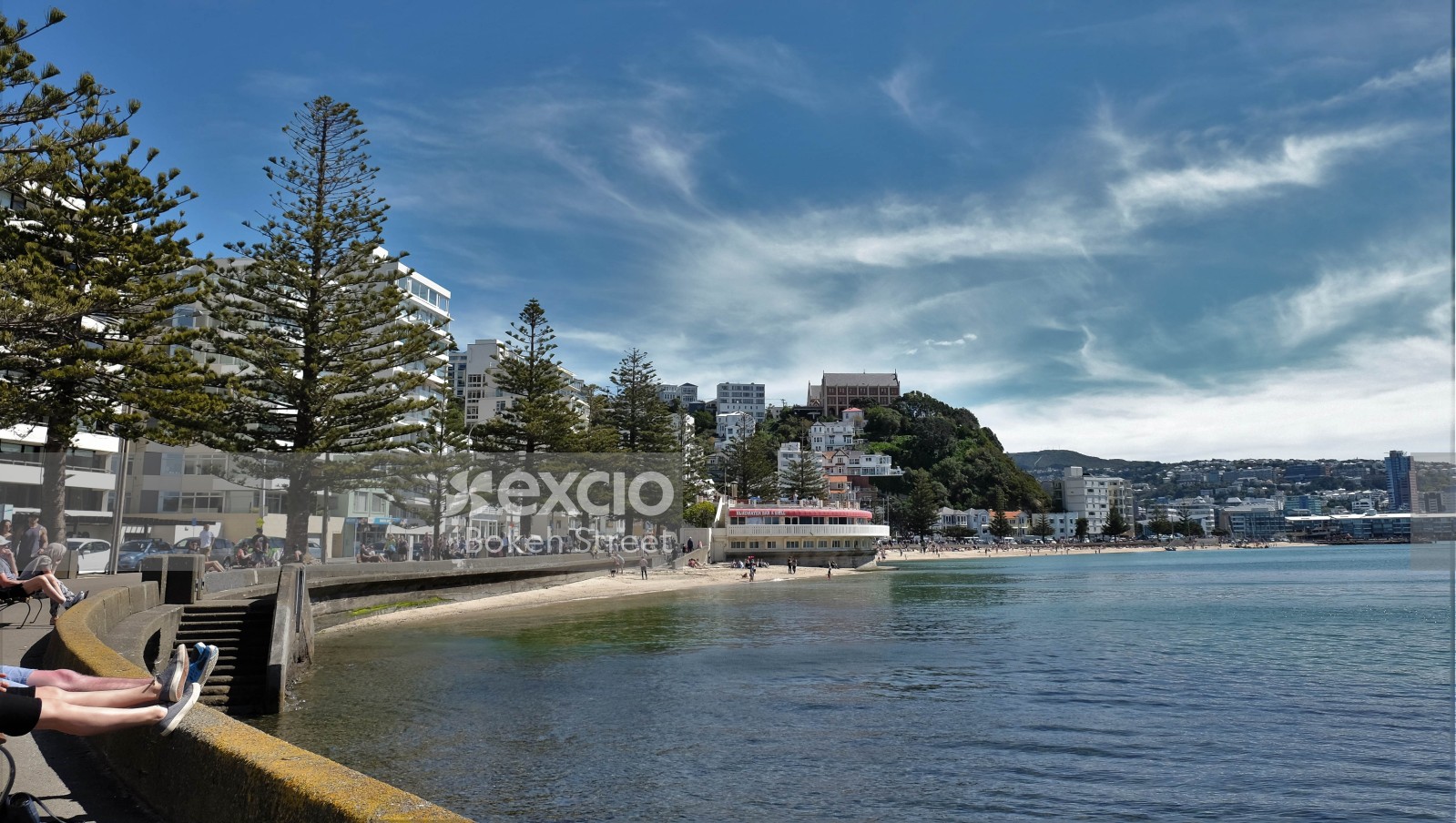 Small beach and waterfront buildings and city skyline surrounding water