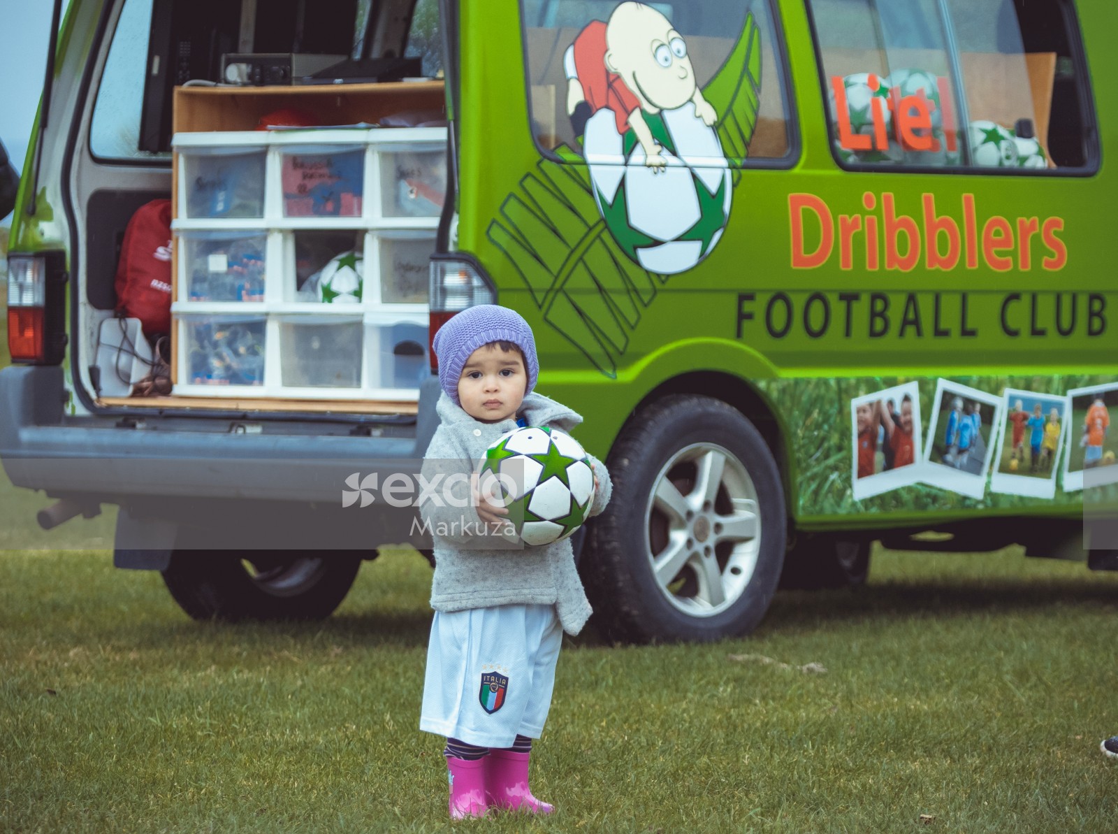 Little girl carrying a football next to Little Dribblers football club van