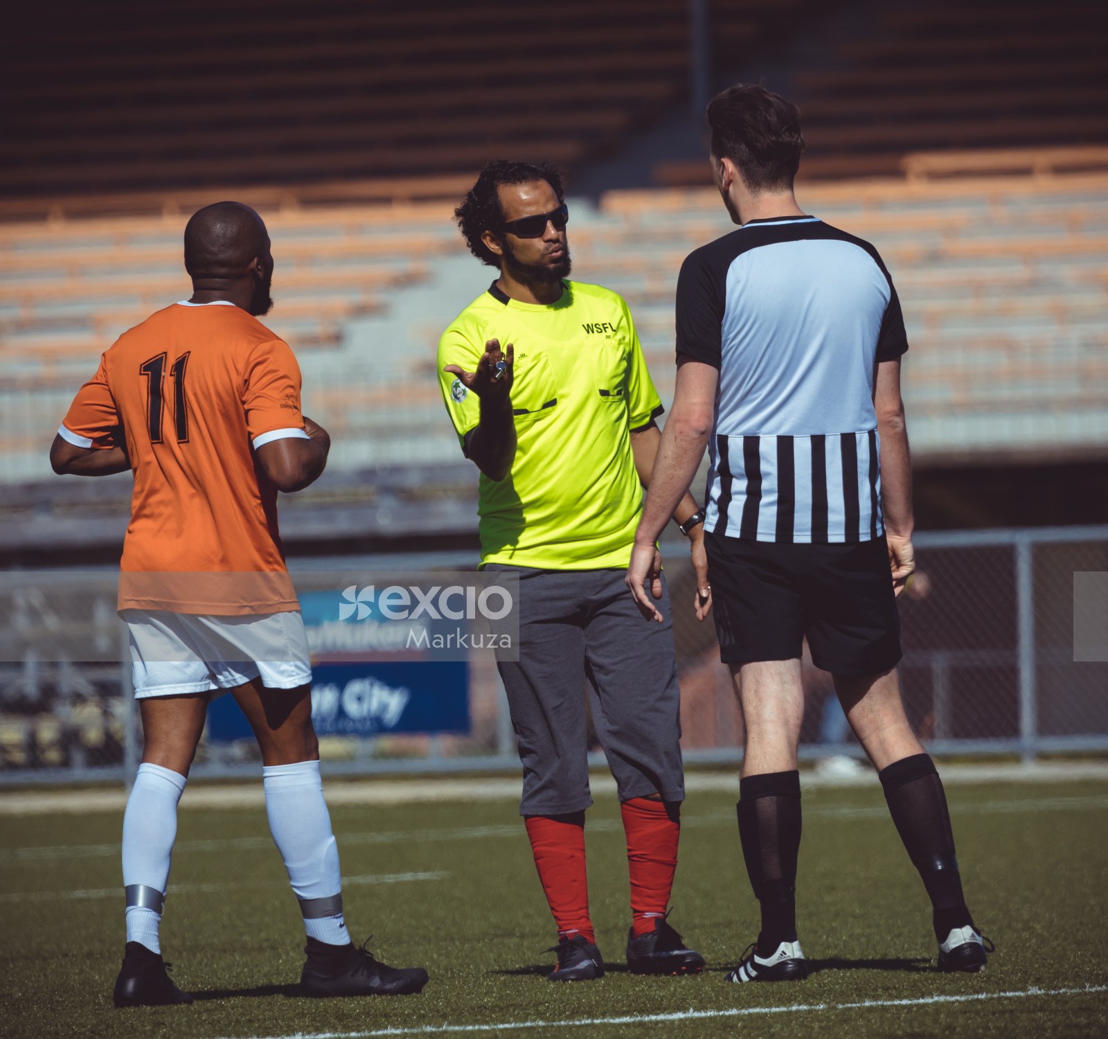 Referee talking to a player in black and white striped shirt - Sports Zone sunday league