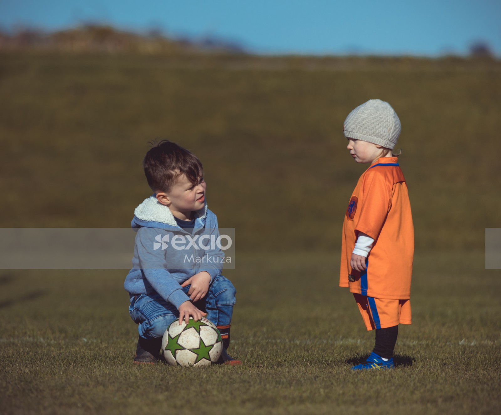 Little boy in blue and girl in orange attire at Little Dribblers soccer match