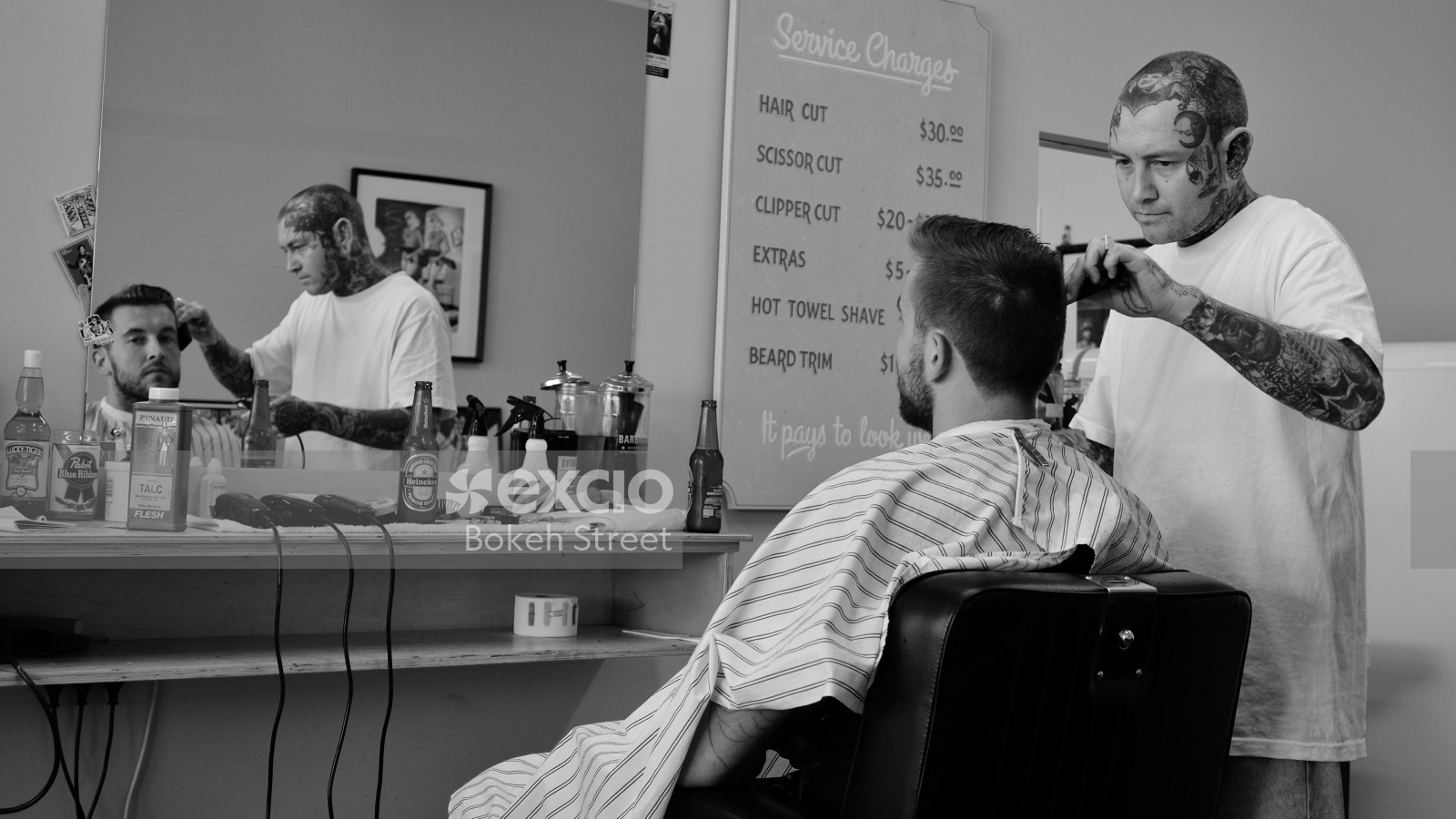 Guy getting a hair trim from a tattooed barber at K' Road monochrome